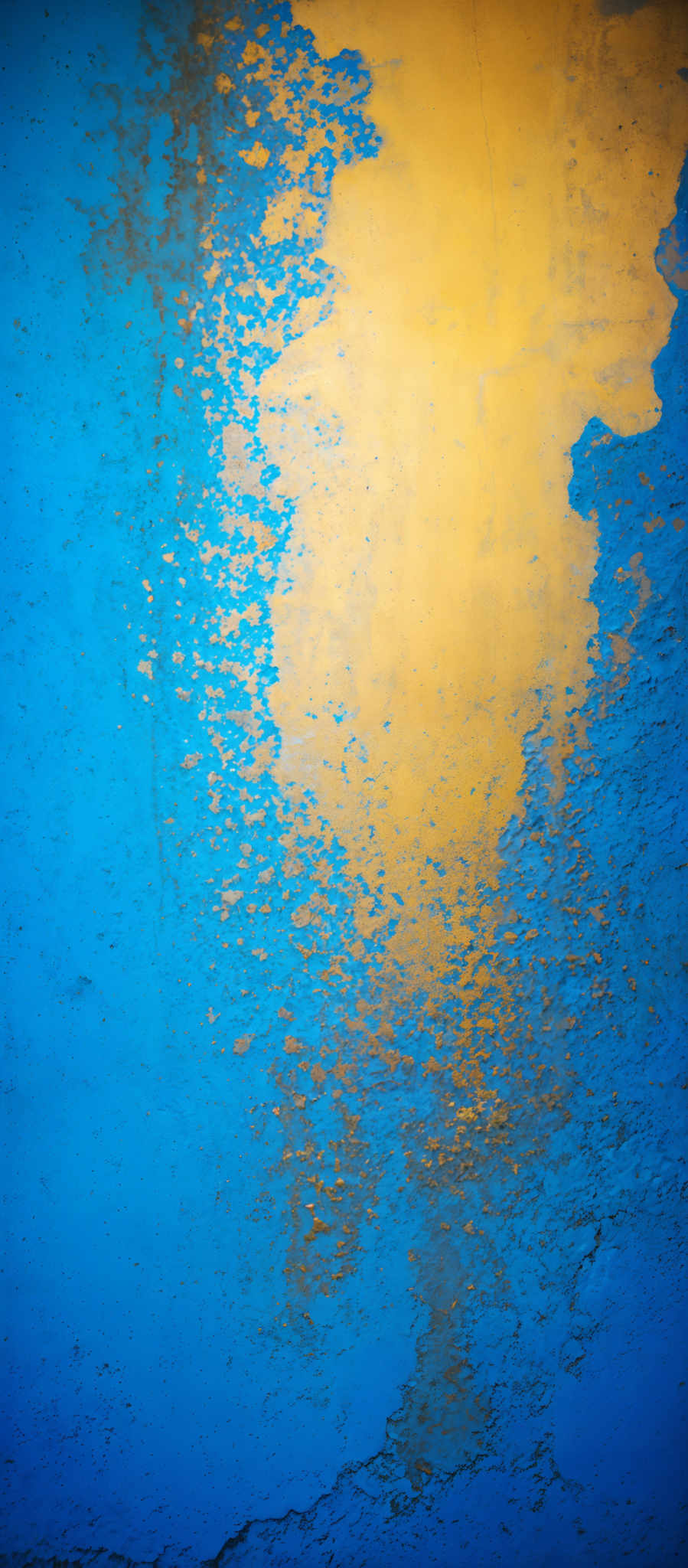 The image showcases a vibrant blue background with patches of peeling paint revealing a golden-yellow hue beneath. The golden- yellow patches appear to be irregularly shaped, with some areas having a more concentrated distribution of color than others. The blue background has a rough texture, with visible cracks and unevenness, suggesting wear and age.