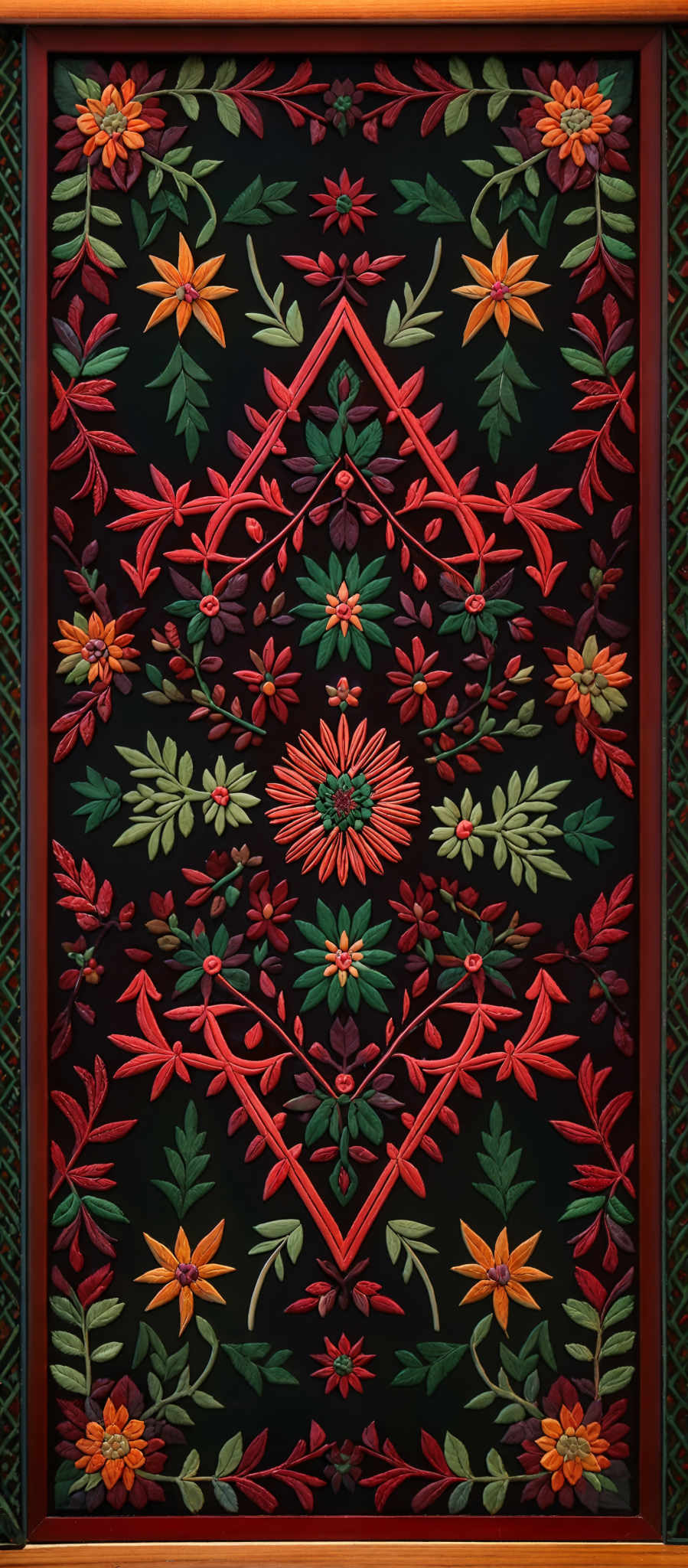 The image showcases a vibrant and intricate design, predominantly in shades of red, green, and orange. The design features symmetrical patterns with floral motifs, including flowers and leaves. The central motif is a large, radiant flower surrounded by smaller flowers and foliage. The borders of the design are adorned with a crisscross pattern, and the entire artwork is framed with a wooden border.