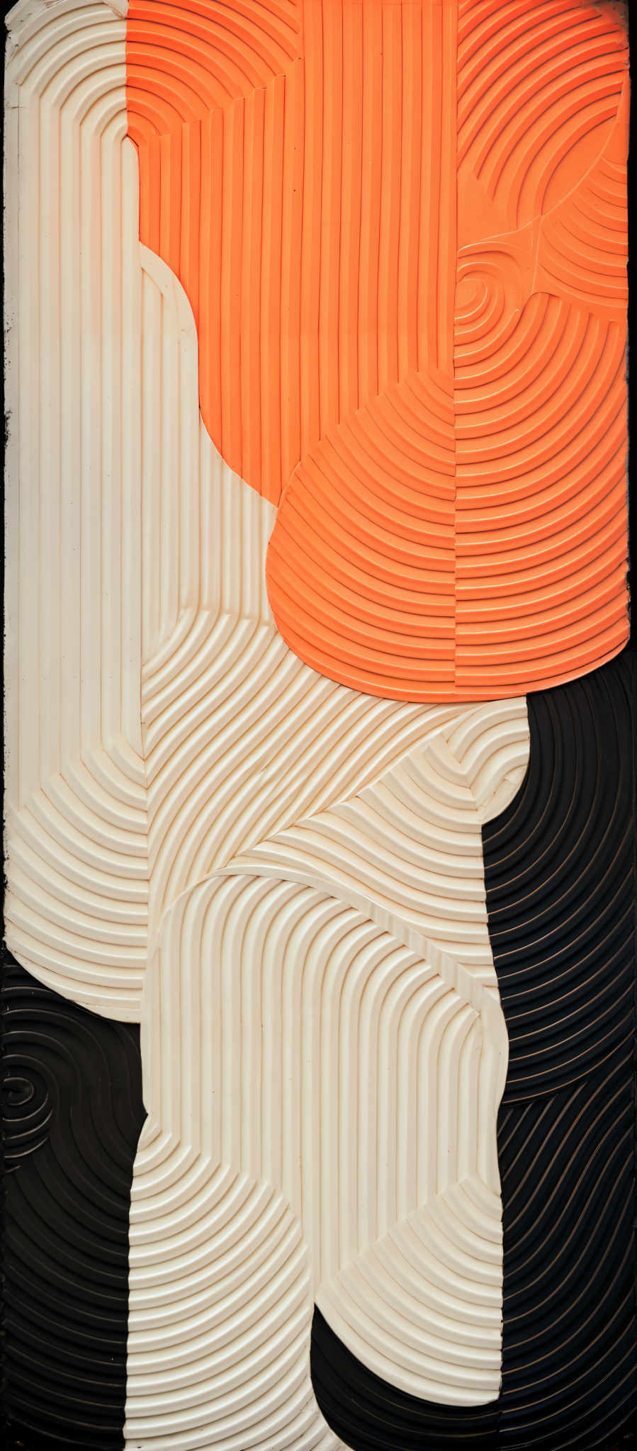 The image showcases a three-dimensional relief artwork. It predominantly features a combination of white, orange, and black colors. The white and orange sections have intricate, raised, and curved patterns that resemble topographical maps or contour lines. These patterns are organized in a way that creates a sense of depth and dimension. The black section contrasts with the other two, providing a stark contrast and adding a sense balance to the composition.