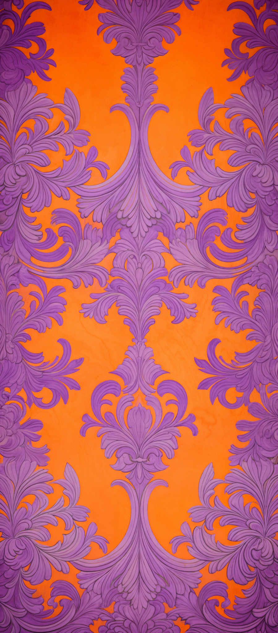 The image showcases a vibrant and intricate design. The dominant colors are a bright orange and a deep purple. The design consists of symmetrical patterns, reminiscent of ornate floral motifs. These motifs are symmetrically arranged, with each pattern having a central vertical element that branches out into elaborate, swirling patterns. The overall effect is both ornate and elegant, evoking a sense of luxury and sophistication.