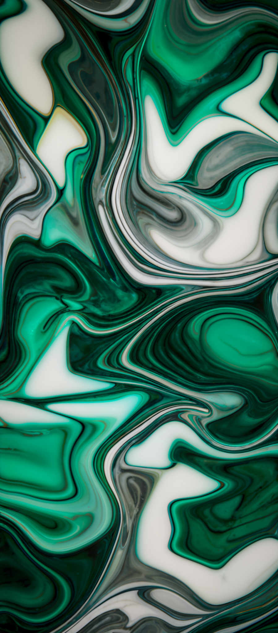 The image showcases a vibrant and intricate pattern of swirling colors. The dominant colors are shades of green, white, and gray. The swirls are fluid and wavy, creating an abstract representation that resembles marbled patterns or fluid art. The shapes are organic and free-flowing, with no distinct forms but rather a blend of colors and patterns that evoke a sense of movement and depth.