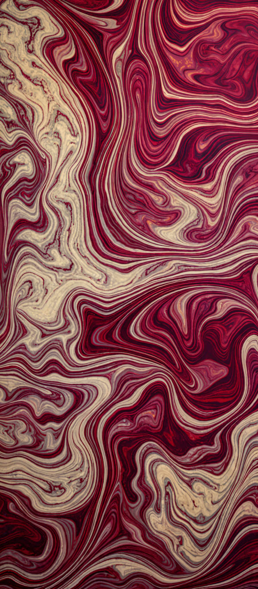 The image showcases a vibrant and intricate pattern of swirling colors. The dominant colors are shades of red, gold, and white. The swirls are fluid and wavy, resembling the flow of liquid or marbled patterns. The design is complex, with the colors intermingling and creating a mesmerizing effect.