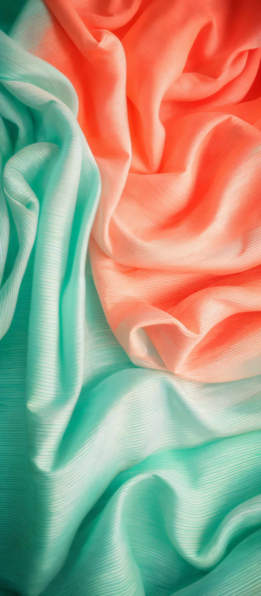 The image showcases a pleated fabric with a rich texture. The colors are a vibrant shade of teal and a warm peach or coral. The teal fabric has a smooth, silky appearance with a subtle sheen, while the coral fabric displays a more matte finish. The pleats in the fabric create dynamic shapes, with some folds rising and others falling, creating a sense of movement and depth.