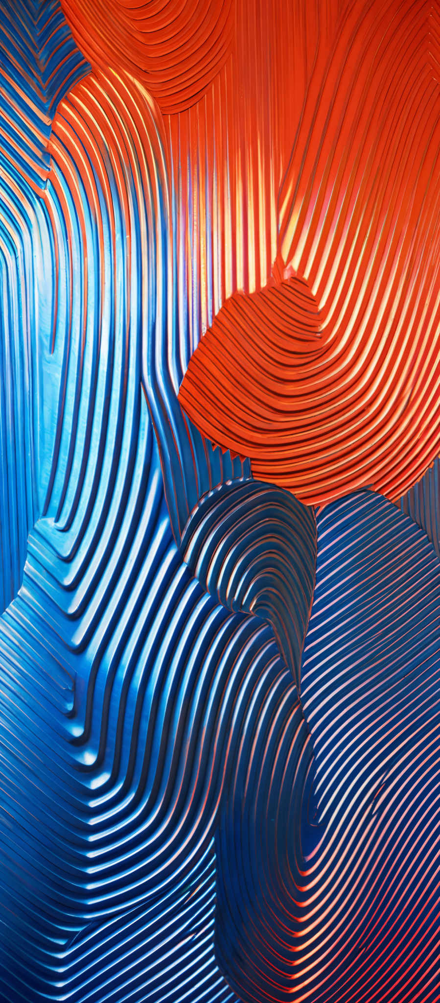 The image showcases a vibrant and intricate design with a combination of blue and red hues. The design consists of wavy, contour lines that create a sense of depth and movement. The blue lines appear cool and serene, while the red lines exude warmth and energy. The overall composition gives an impression of fluidity and dynamism, reminiscent of flowing water or ripples in a pond.