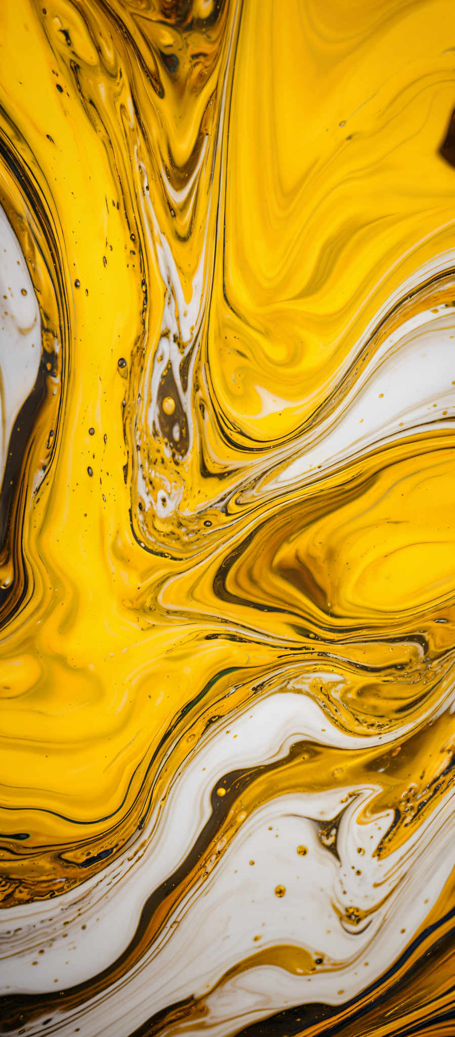 The image showcases a vibrant and dynamic interplay of colors. It predominantly features shades of yellow, white, and black, with swirling patterns that give it a fluid, marbled appearance. The swirls create intricate designs, reminiscent of abstract art or fluid dynamics. The image also contains small bubbles and speckles, adding to its texture and depth.