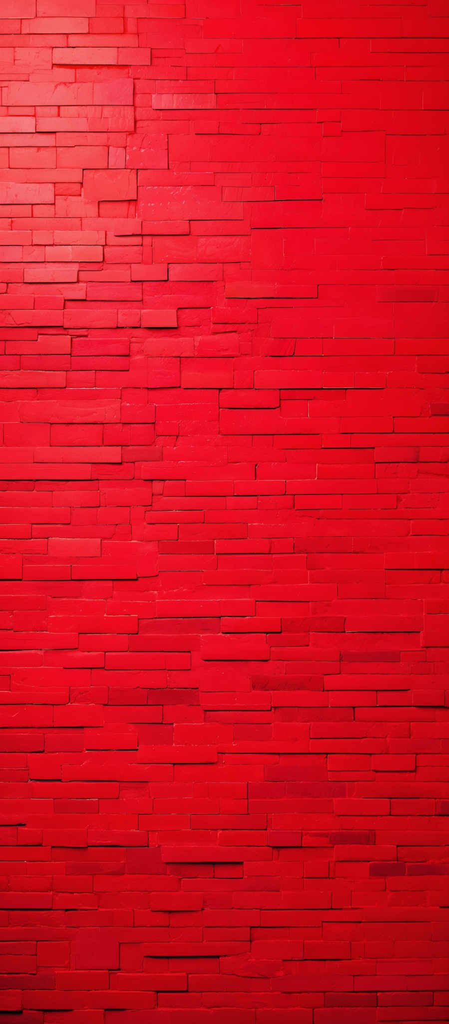 The image showcases a wall made up of rectangular bricks or tiles. The bricks are uniformly colored in various shades of red, ranging from deep crimson to lighter hues. The arrangement of the bricks creates a textured and layered appearance, giving the wall a three-dimensional feel. The overall color palette is dominated by red, creating a warm and vibrant ambiance.