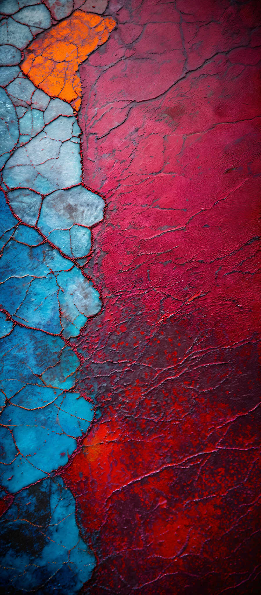 The image showcases a vibrant and textured surface. The dominant colors are shades of red, blue, and orange. The texture appears to be cracked and layered, resembling dried mud or clay. The cracks are filled with a mix of colors, creating a mosaic effect. The blue and orange sections are more pronounced and appear to be filled with some kind of substance, possibly paint or a liquid, that has solidified.