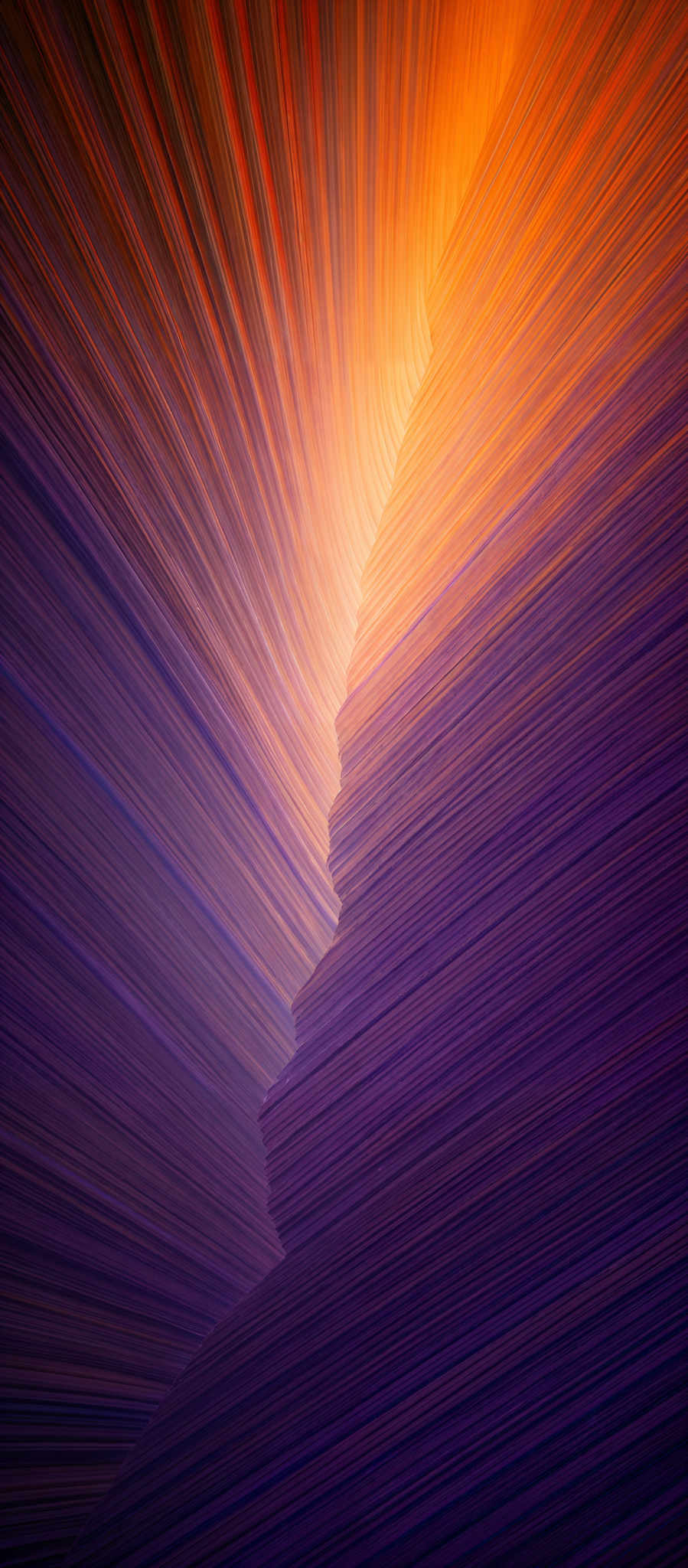 The image showcases a vibrant and dynamic pattern of colors. It features a gradient transition from deep purples at the top to bright oranges and yellows at the bottom. The pattern appears to be a series of layered, curved lines that converge towards the center, creating a sense of depth and movement. The overall shape resembles a funnel or a wave, with the colors swirling and flowing in a harmonious manner.