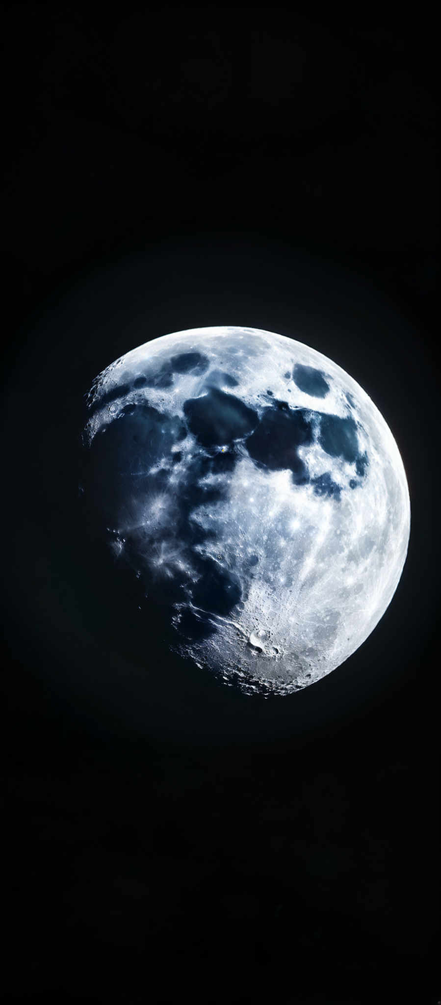 The image showcases a celestial body, which appears to be the moon. It is predominantly a pale blue-white color, with darker shades representing the moon's craters and shadowed areas. The moon'sm surface is dotted with numerous craters, some of which are larger and more prominent, while others are smaller and more subtle. The darker regions suggest areas where the moon is not directly illuminated by the sun.