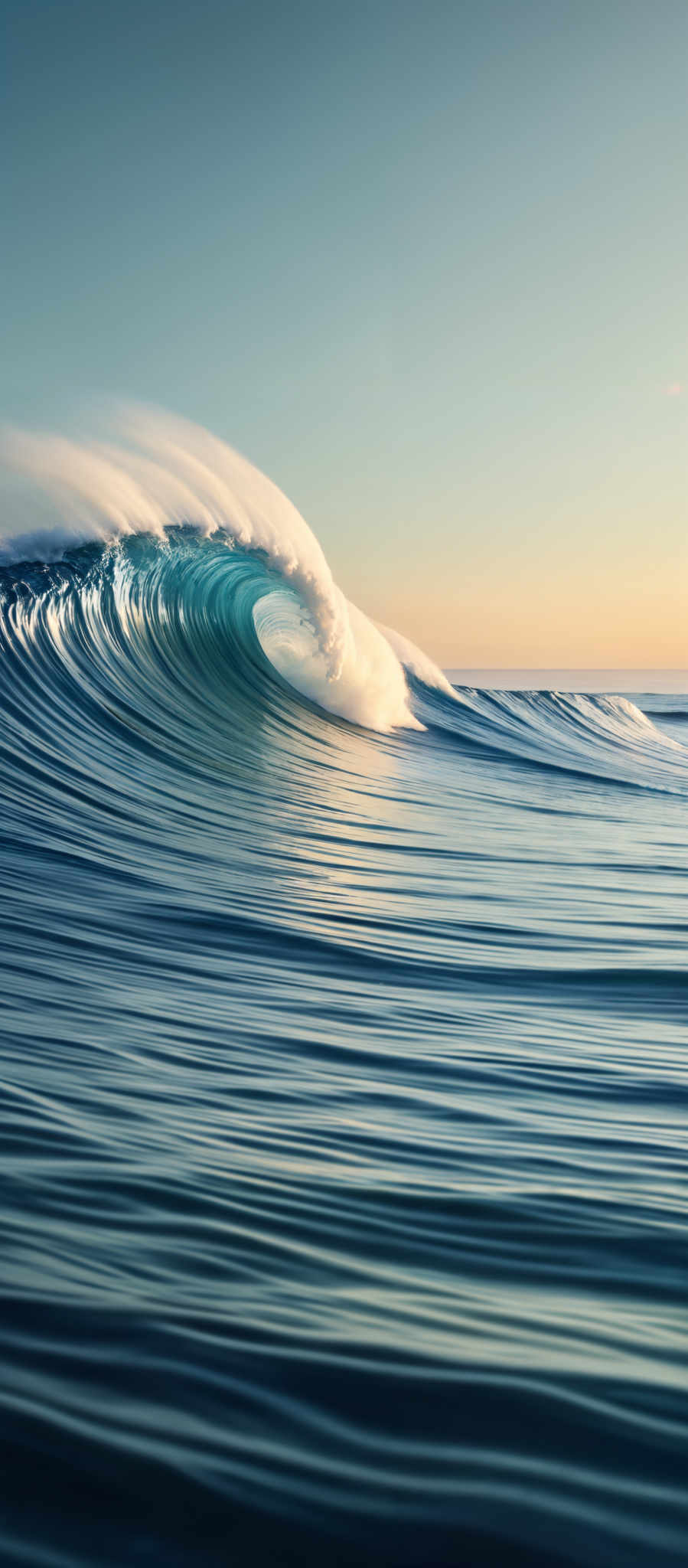 The image showcases a beautiful ocean scene with a large wave curling over. The wave is a vibrant shade of turquoise, contrasting with the deeper blue of the ocean. The sunlight reflects off the wave, creating a shimmering effect. The sky above is clear with a gradient of colors, transitioning from a light blue at the top to a warm orange near the horizon, suggesting either a sunrise or sunset.