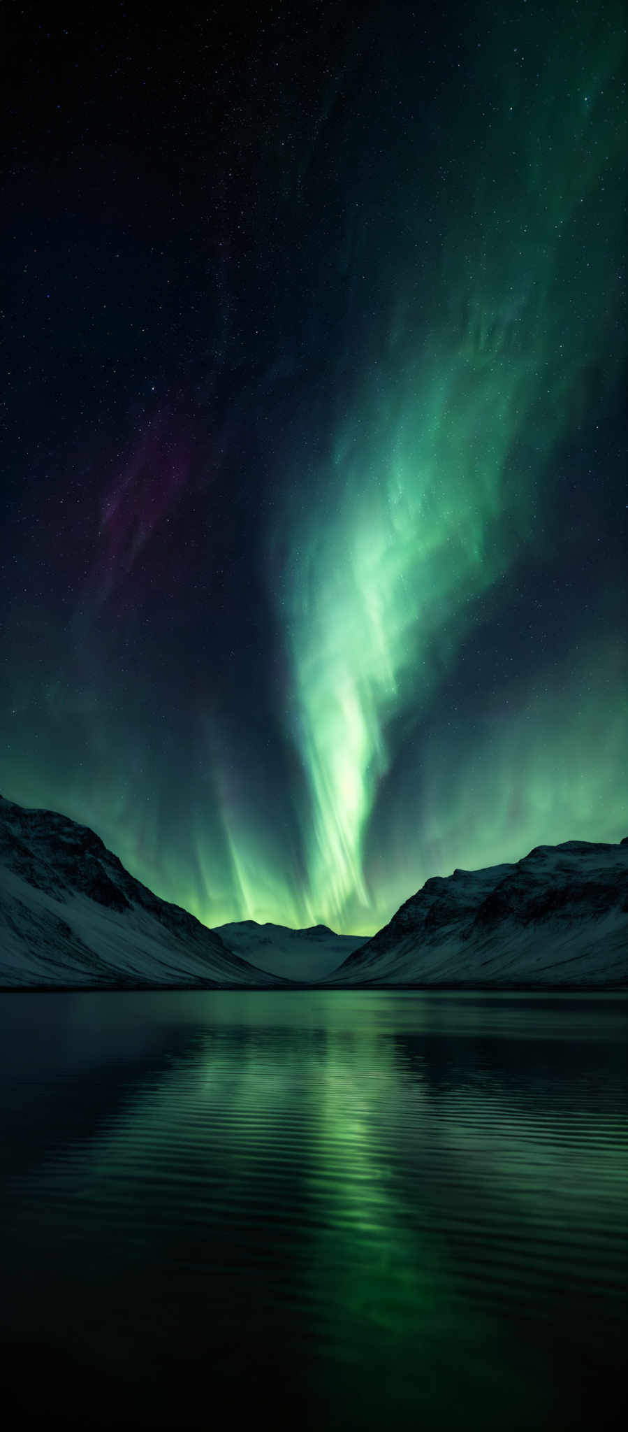 The image showcases a breathtaking view of the Northern Lights, also known as the Aurora Borealis. The lights display a vibrant green hue, with subtle hints of purple and pink. They appear as ethereal streaks and waves, cascading down from the night sky and reflecting on a calm body of water below. The sky is dotted with numerous stars, adding to the celestial beauty of the scene. The landscape is dominated by snow-covered mountains, which provide a stark contrast to the luminous display of the auroras.