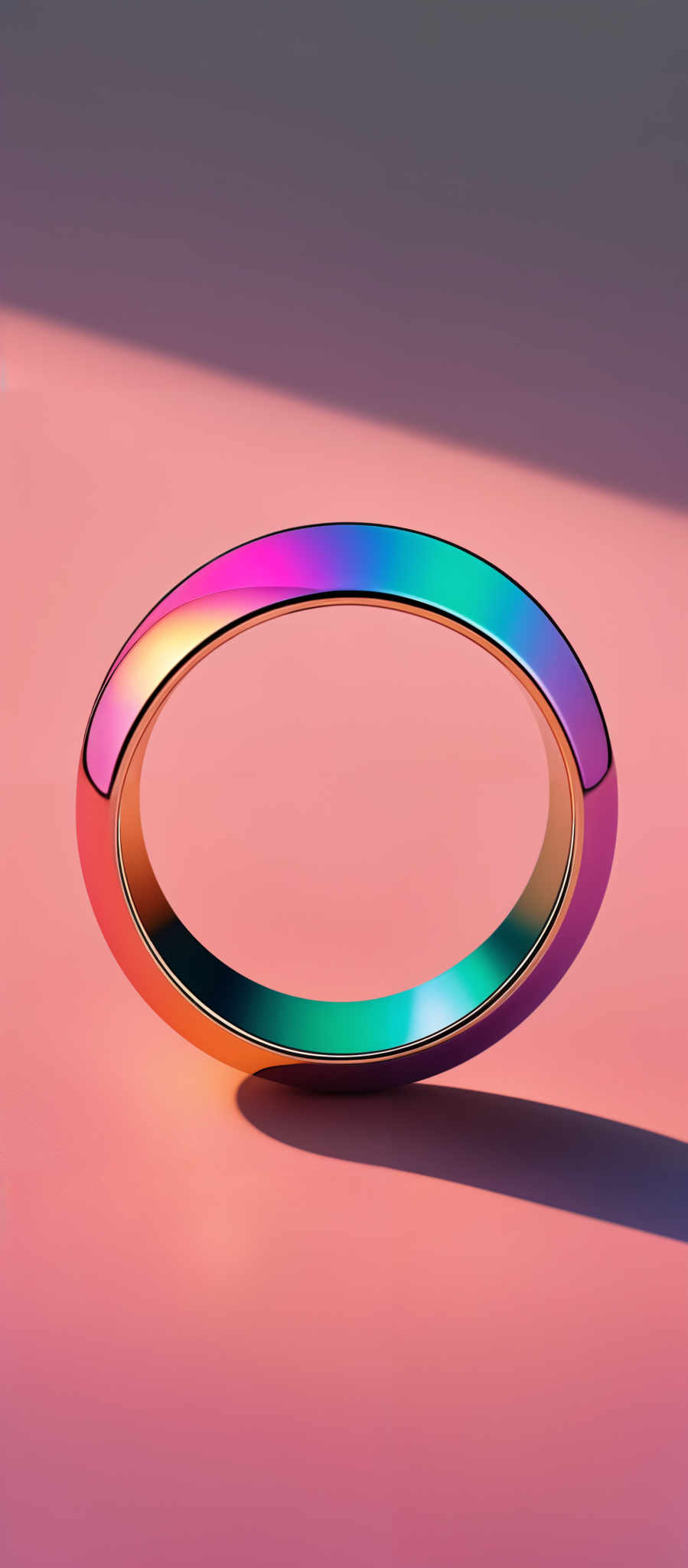 The image showcases a multicolored, rainbow-like ring that appears to be hovering or placed on a surface. The ring has a smooth, reflective surface that mirrors the colors of the spectrum, transitioning from red at the top to blue at the bottom. The background is a gradient of pink and purple hues, creating a contrast that accentuates the vibrancy of the ring's colors.