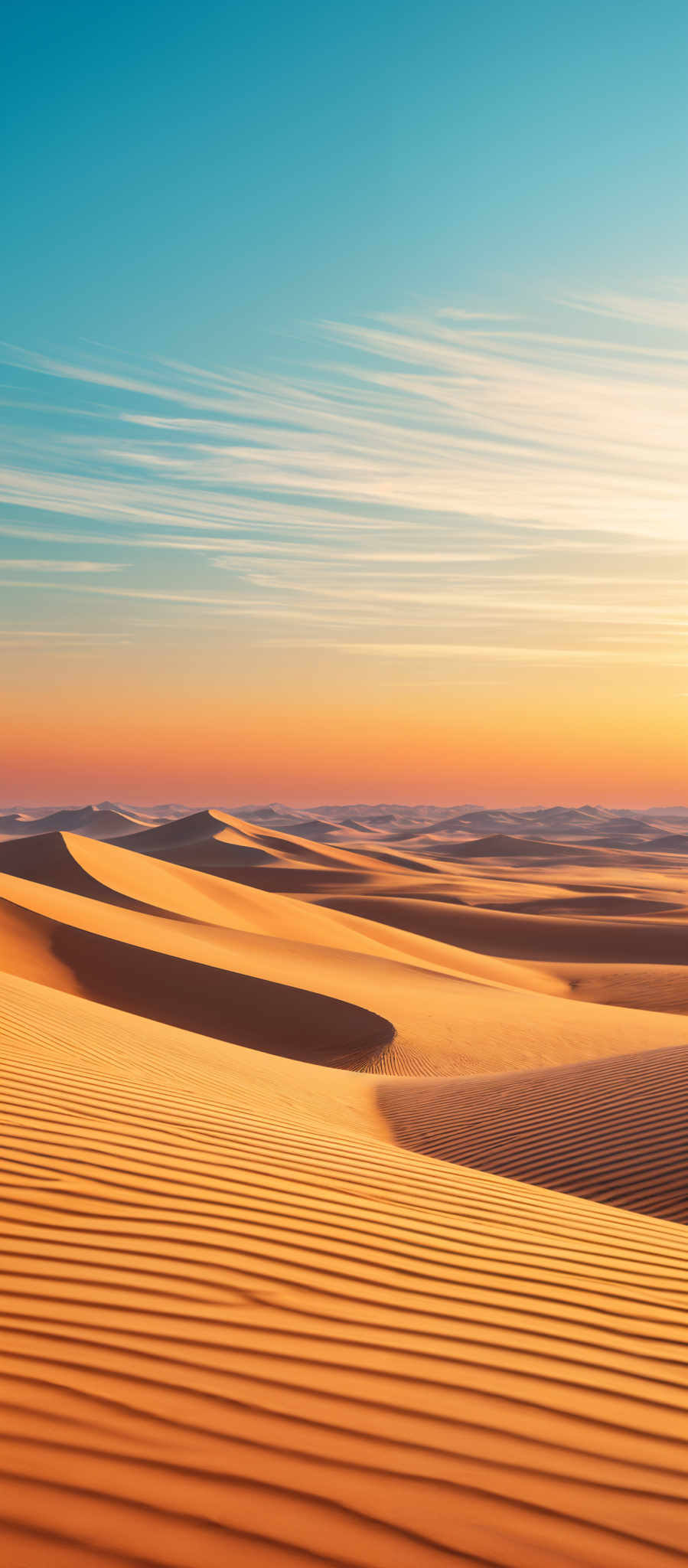 The image showcases a vast desert landscape during what appears to be either sunrise or sunset. The dominant colors are shades of orange, gold, and deep blue. The sand dunes are beautifully illuminated, casting long shadows and displaying intricate patterns formed by the wind. The sky is painted with streaks of white clouds, and the horizon showcases the transition from the warm hues of the sky to the cooler tones of the desert below.