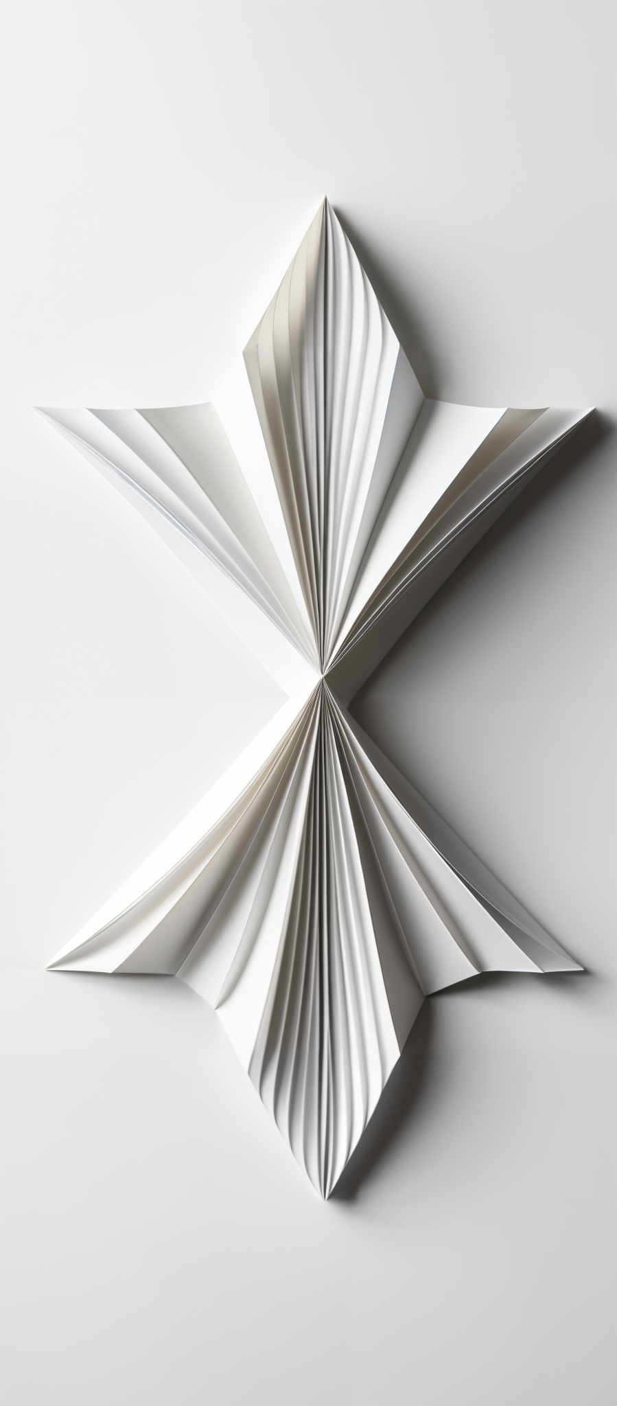 The image showcases a symmetrical, intricate design made of white paper. The design appears to be a radial pattern with multiple layers of paper folded inwards, creating a fan-like appearance. The paper has a smooth texture, and the folds are sharp and well-defined, giving the design a structured and elegant look.