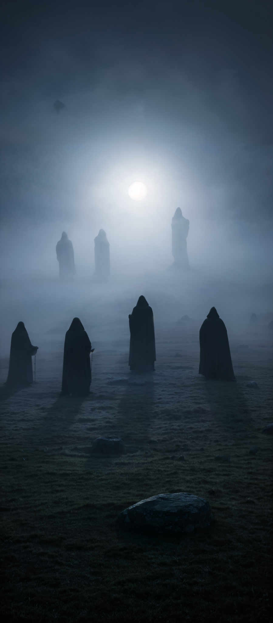 The image predominantly features cool and muted tones, with a blend of blues and grays. The central figure is a bright white, possibly representing a light source or a celestial body, surrounded by a thick layer of mist or fog. The ground is covered with what appears to be grass or moss, and there are several large, flat stones scattered around. In the foreground, there are multiple figures draped in dark cloaks, standing with their backs to the viewer, facing the central light. The overall atmosphere is mysterious and ethereal.