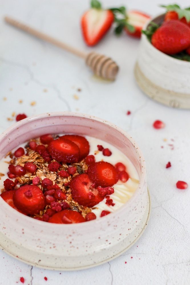 Yoghurt granola bowl with strawberries, pomegranate and raspberry
