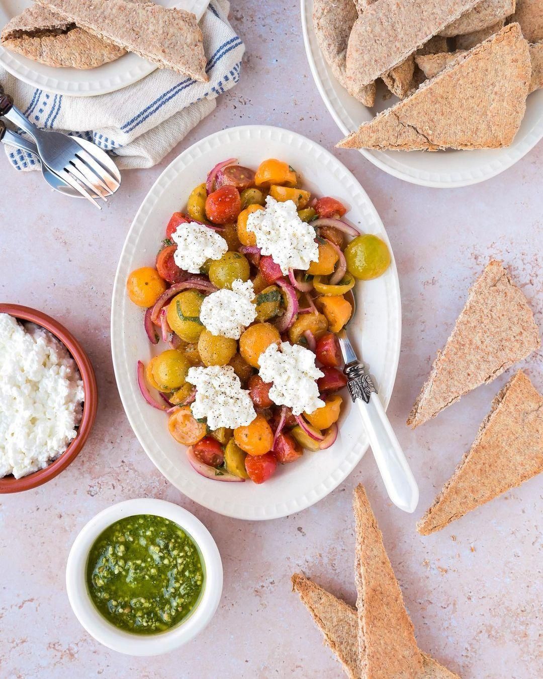 Whole wheat crackers with marinated tomatoes, cottage cheese and pesto