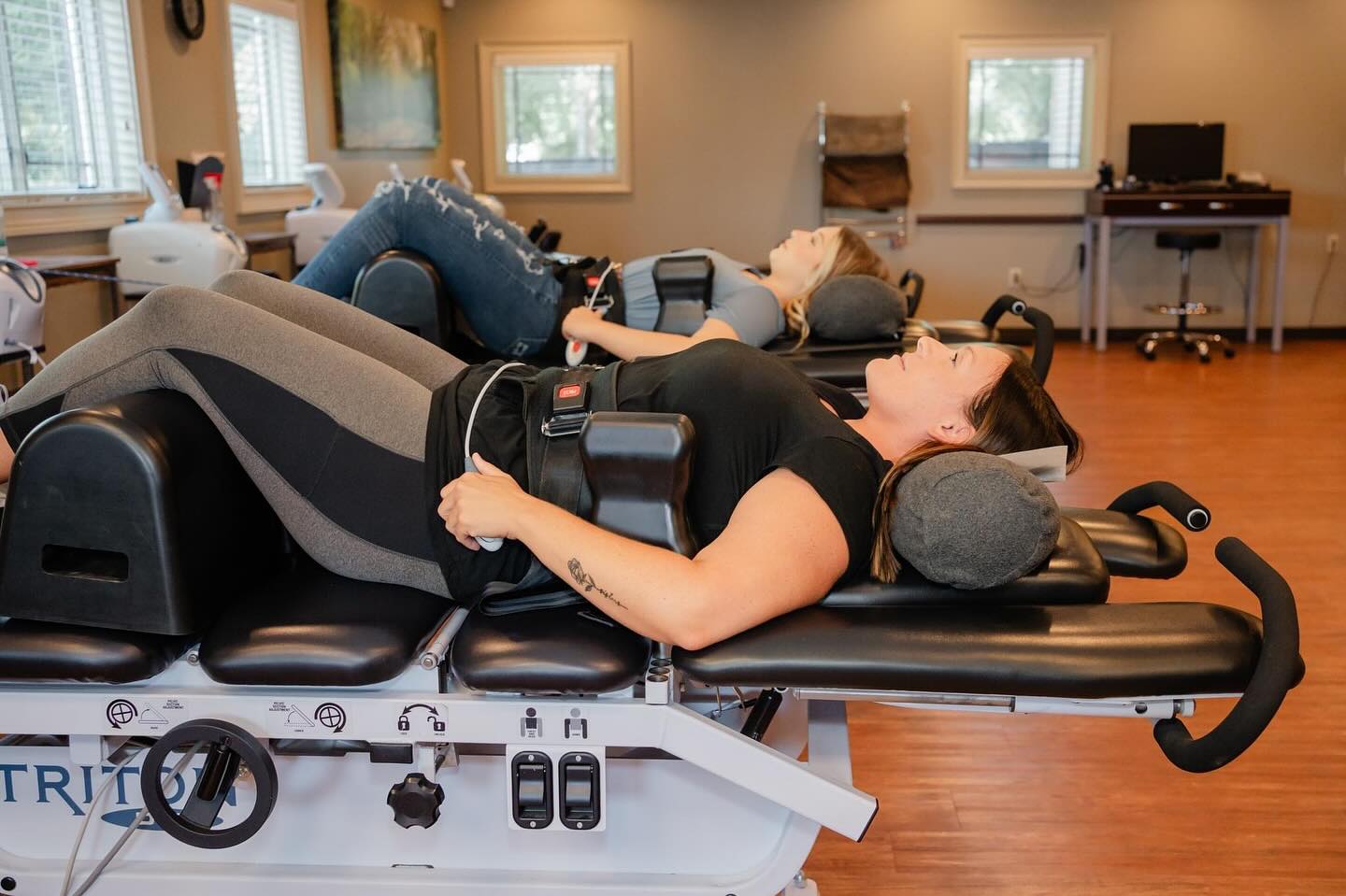 Two patients undergo non-surgical spinal decompression therapy on Triton traction tables at Pray Chiropractic's office