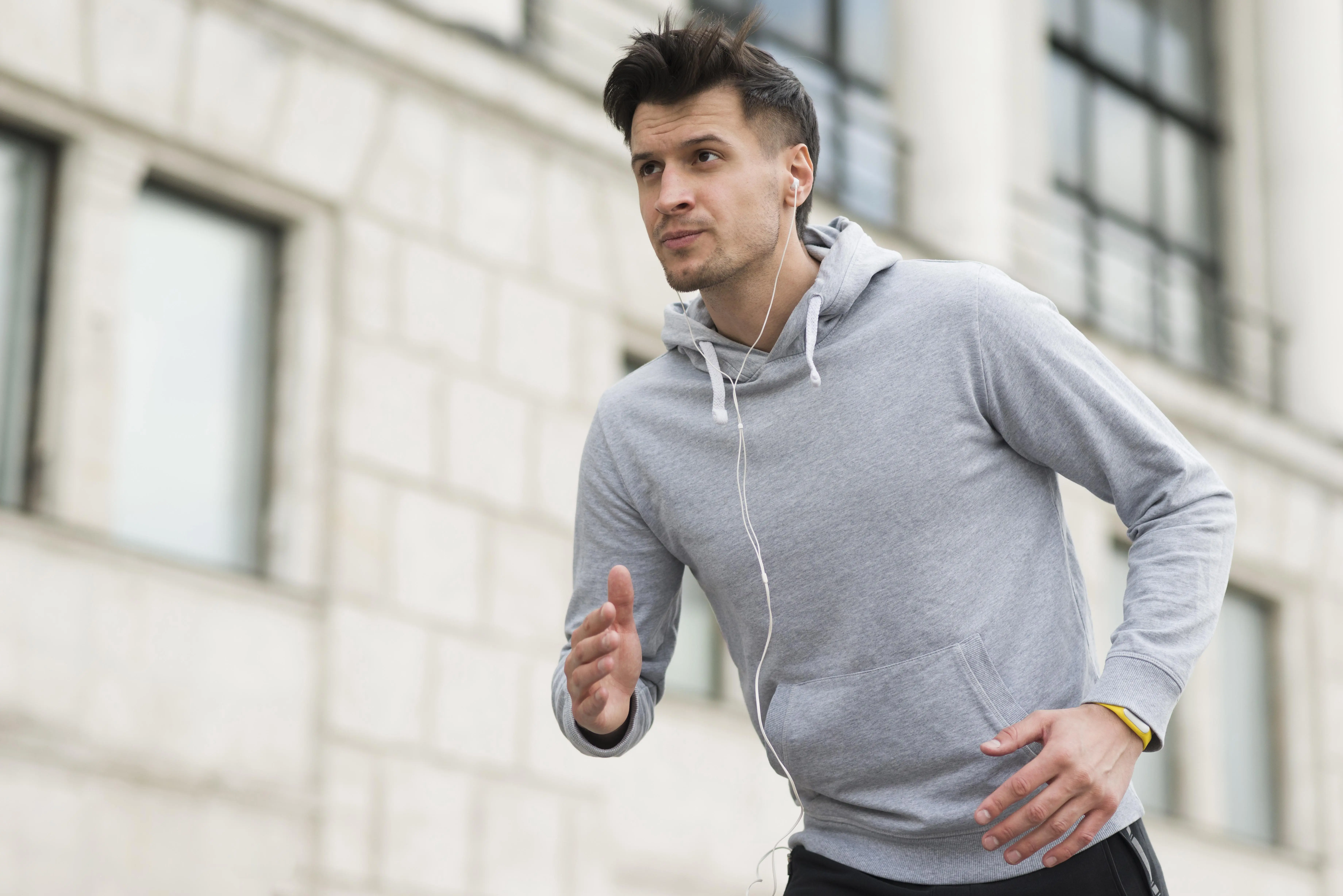 Man in a gray hoodie jogging on a city street for heart health