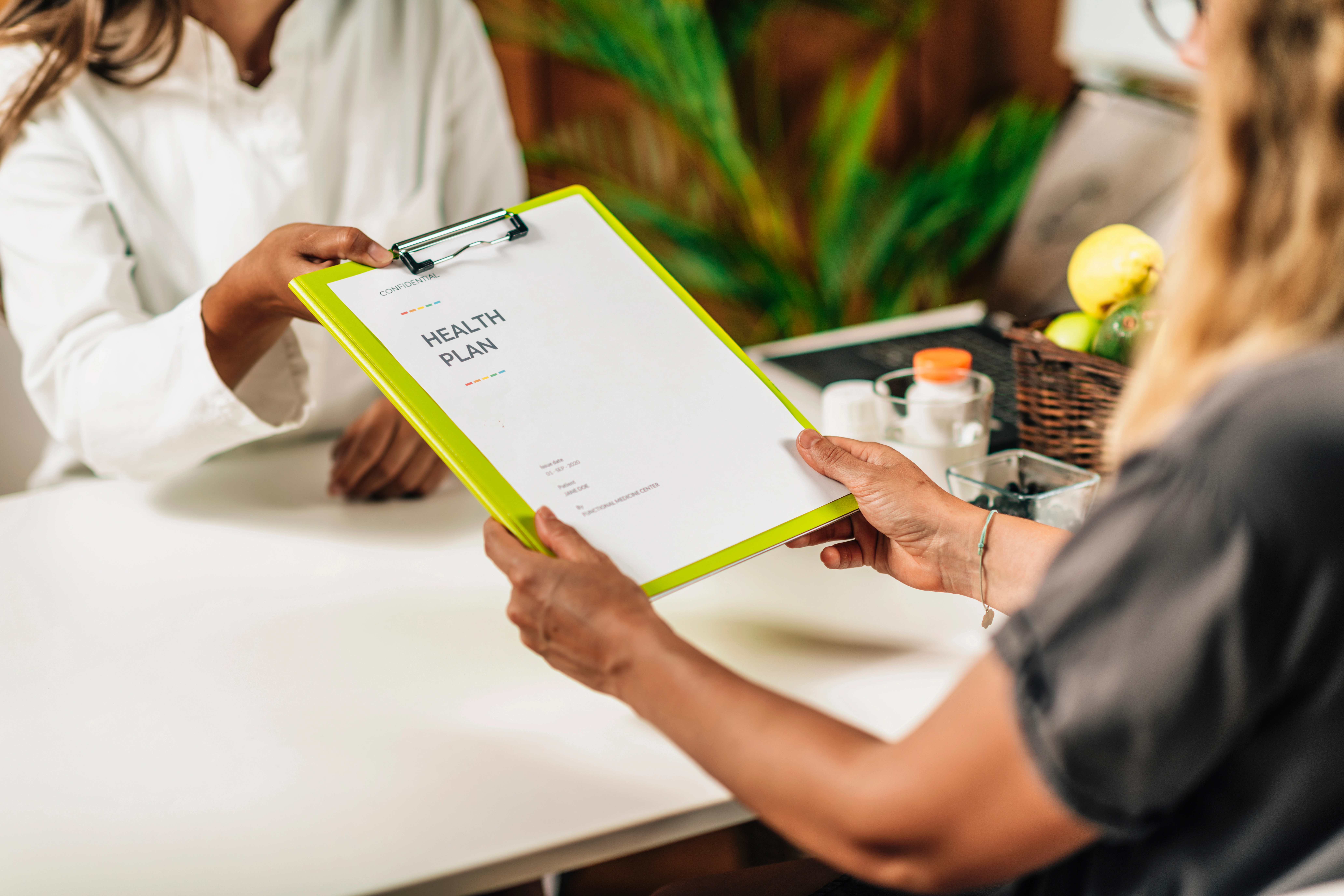 A provider hands a patient a clipboard with a health plan document during a nutrition consultation