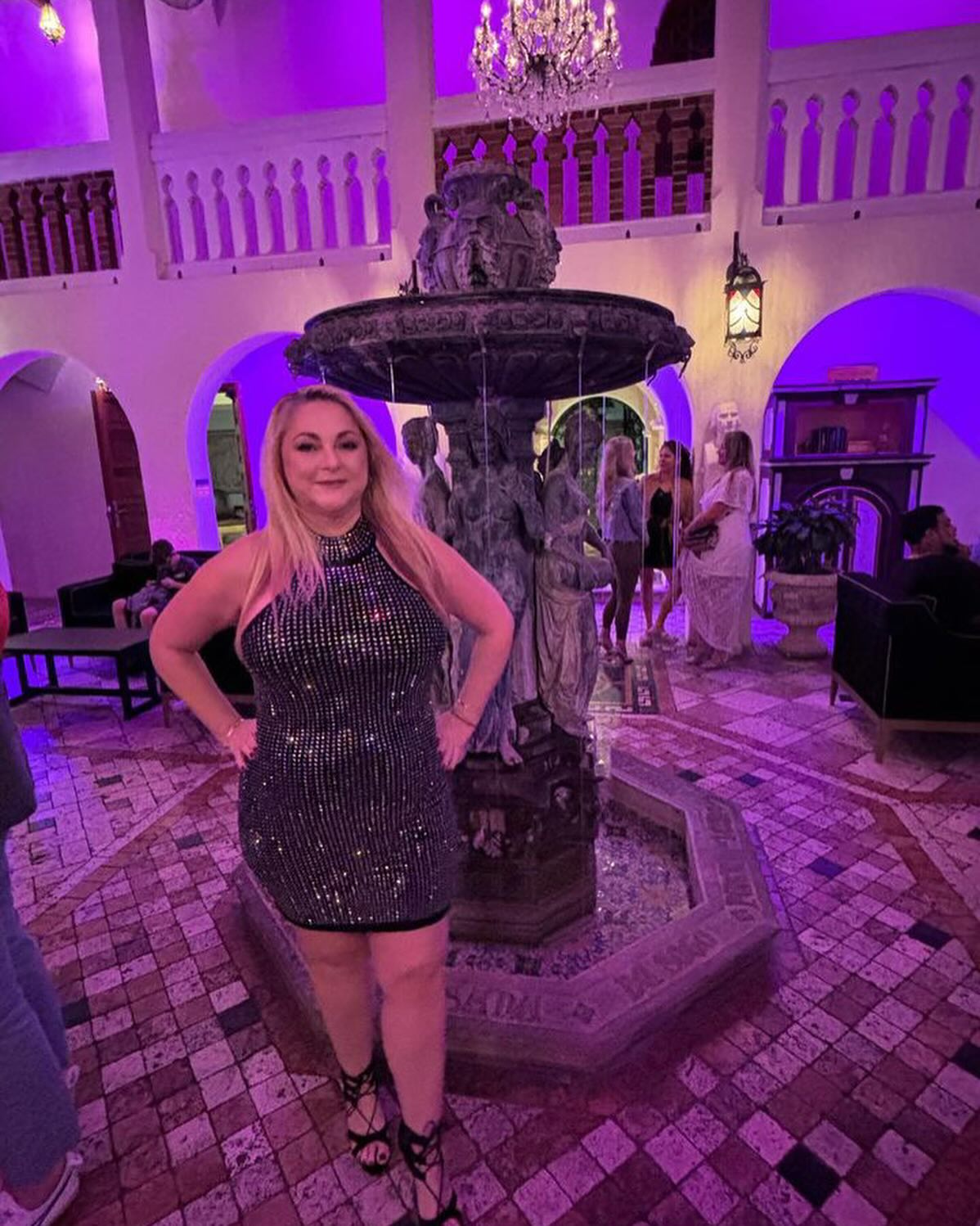 A smiling gastric sleeve patient in a fitted sequined dress at an evening event after her weight loss