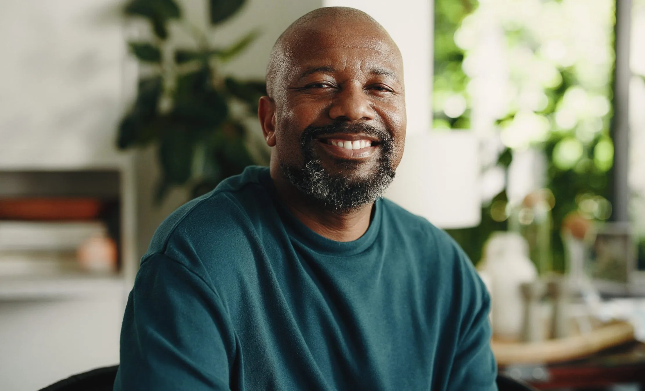 Smiling middle-aged man sitting in a bright home setting, used to illustrate depression treatment content