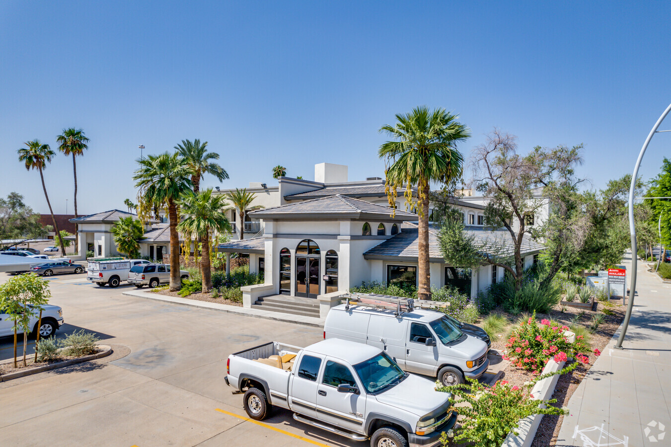 Exterior daytime photo of a medical office building with palm trees, landscaping, and a parking lot with vehicles