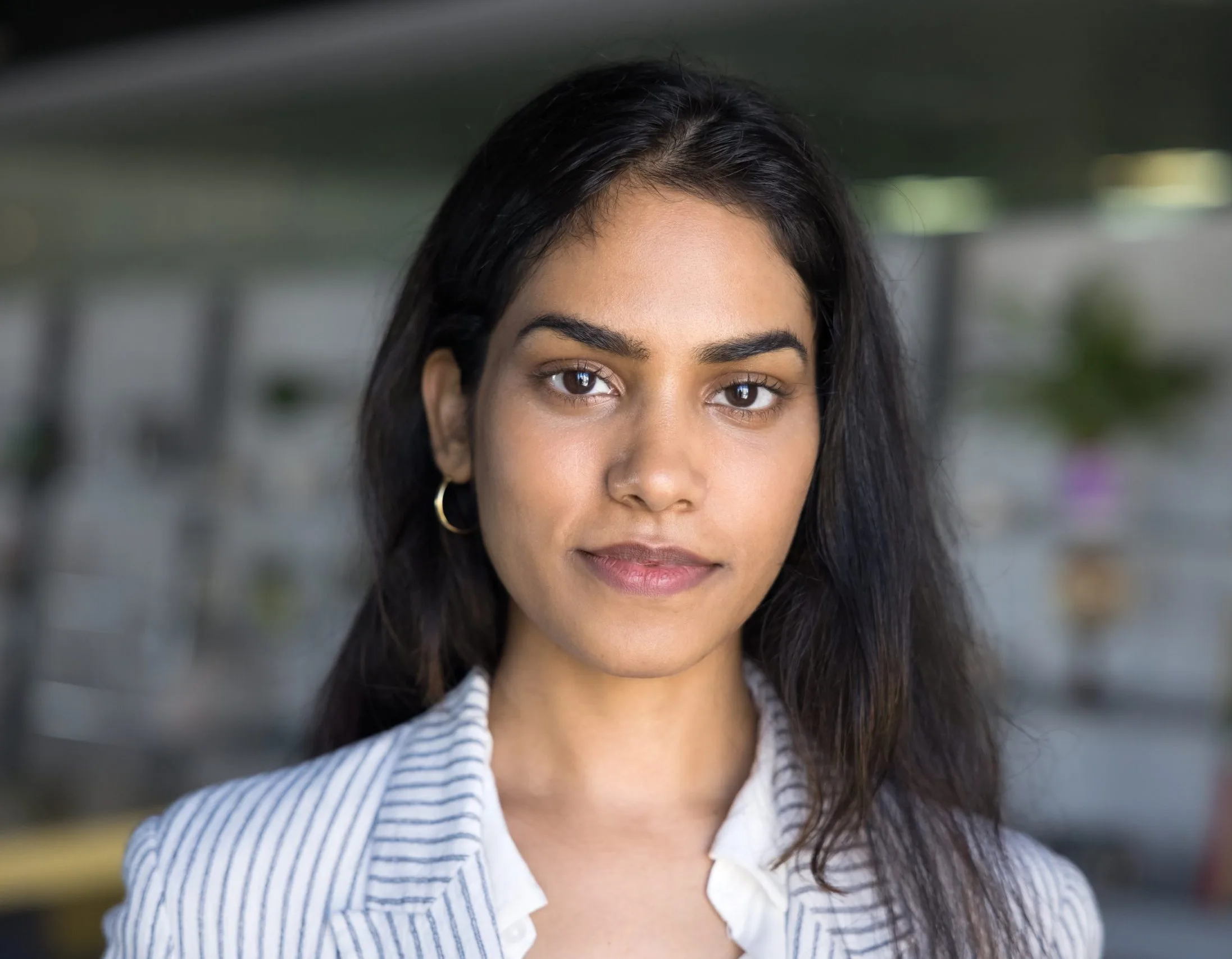 Close-up portrait of a young woman in a striped blazer looking directly at the camera, used to illustrate family relationship