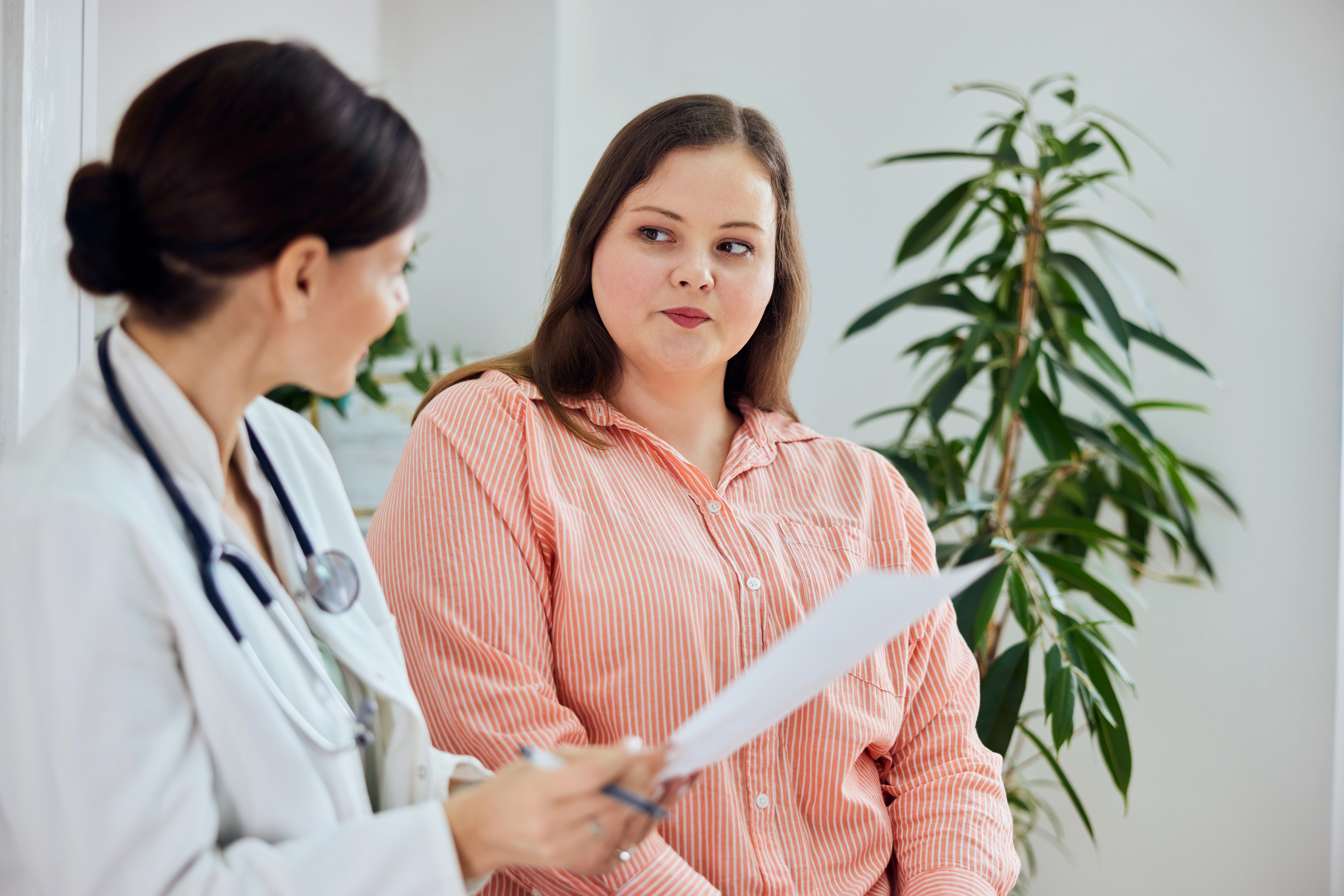 Physician in a white coat reviewing paperwork with a female patient during a consultation