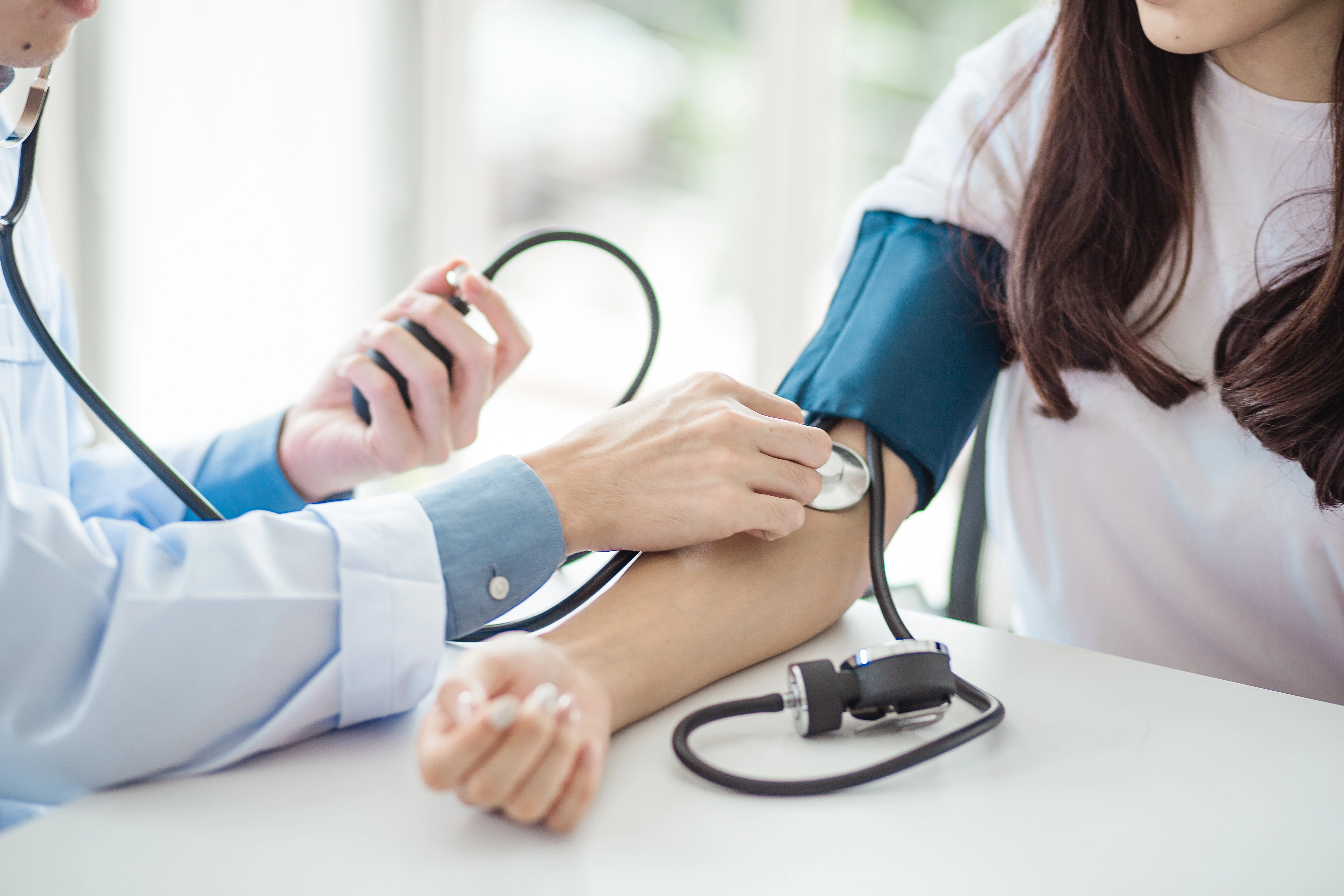 A doctor measures a patient's blood pressure using a cuff and stethoscope during a checkup.