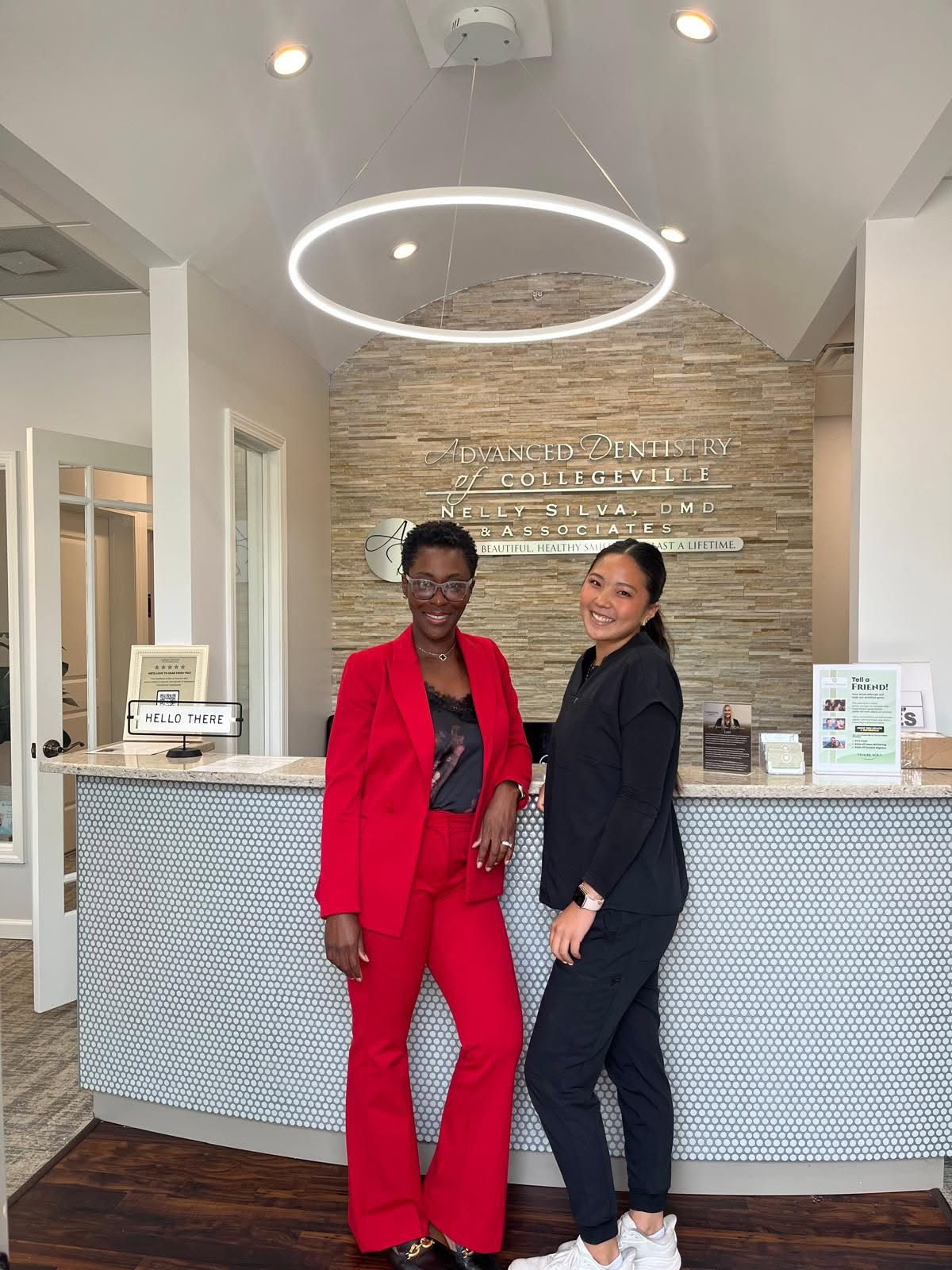 Dr. Nelly Silva and a team member smiling at the front desk of our dental office