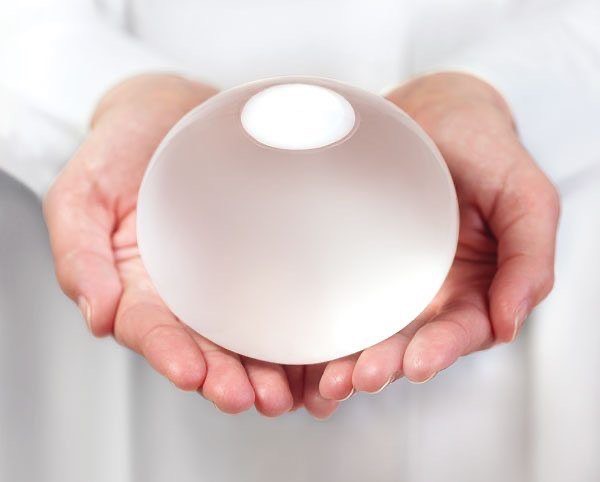 Gloved hands holding a filled ORBERA gastric balloon, showing its soft round shape and size