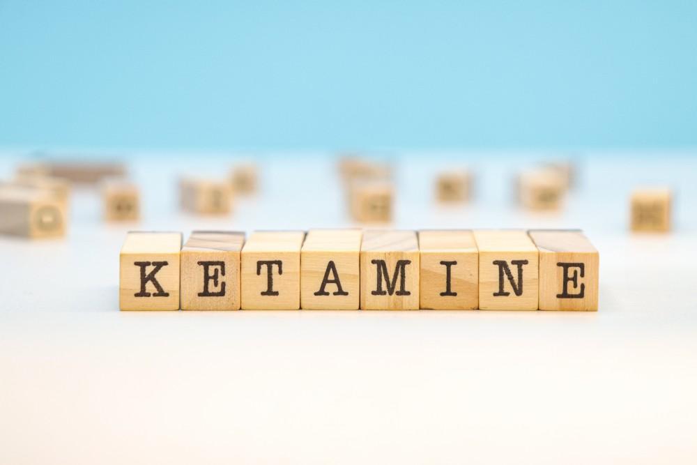 Wooden letter blocks spelling KETAMINE on a white surface against a blue background, illustrating a blog post about preparing