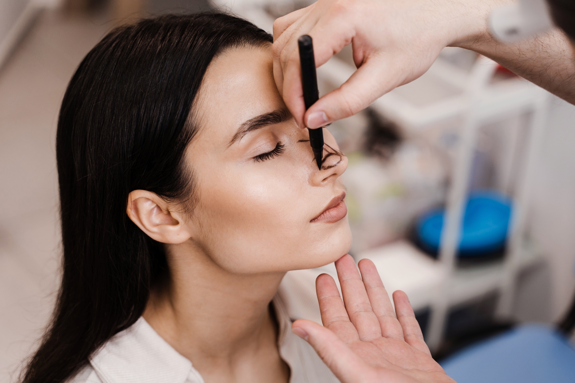 A provider marks pre-surgical rhinoplasty guidelines on a woman's nose with a pen before her procedure