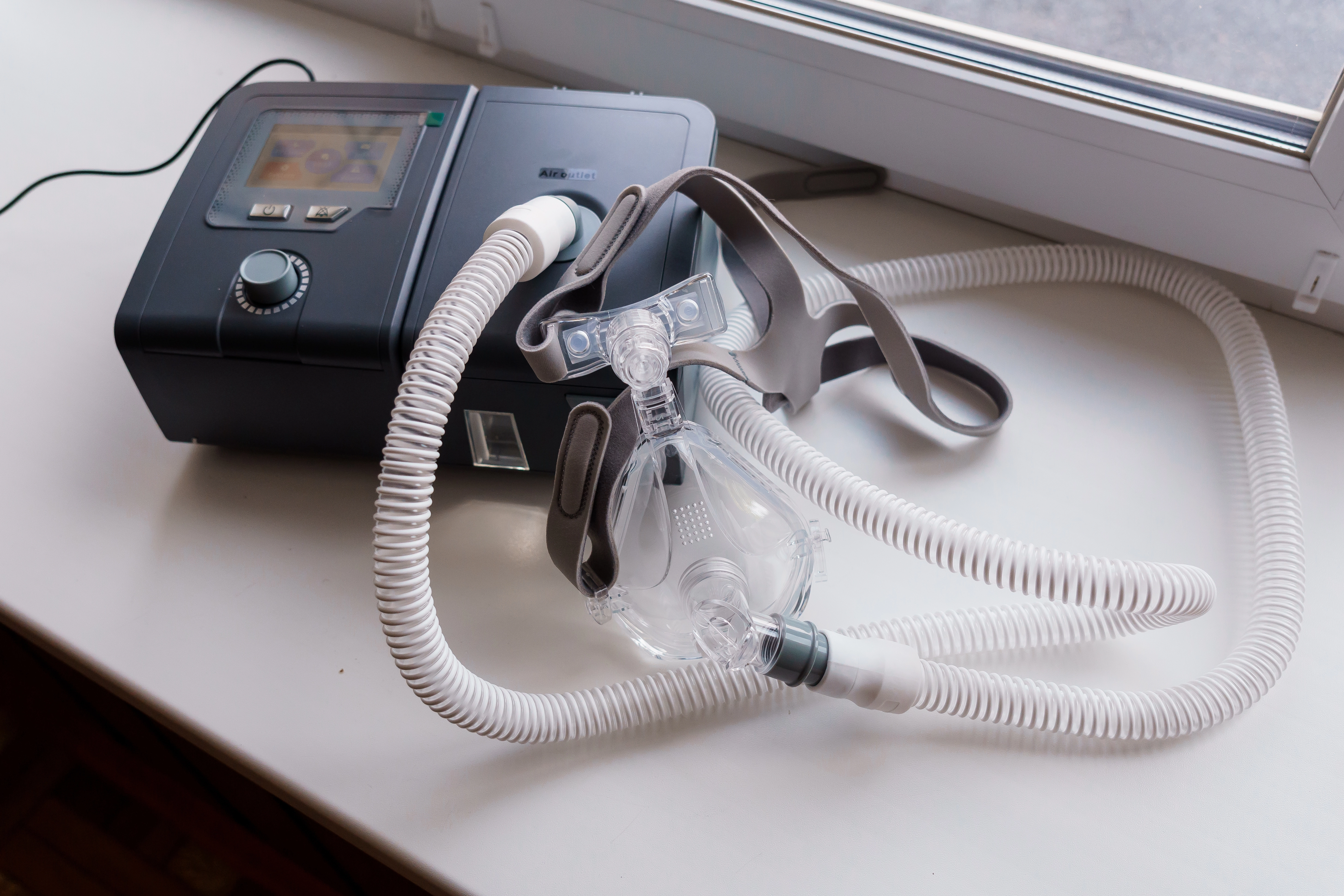 A CPAP machine with mask and tubing sits on a table, used as a banner image for an article on sleep apnea and high blood pres
