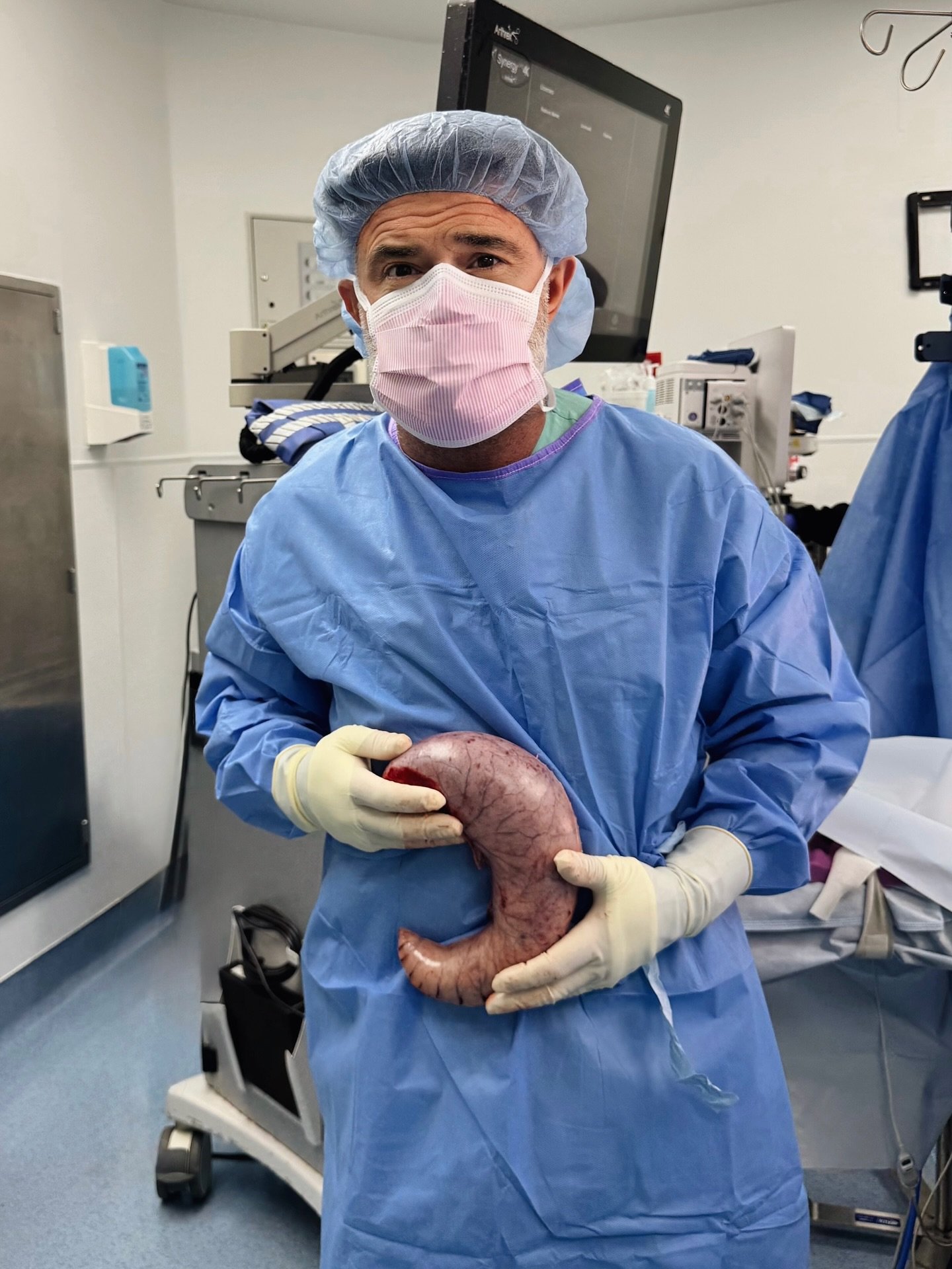 Dr. Keshavarzi in surgical gown, cap and mask holding a stomach model in our operating room