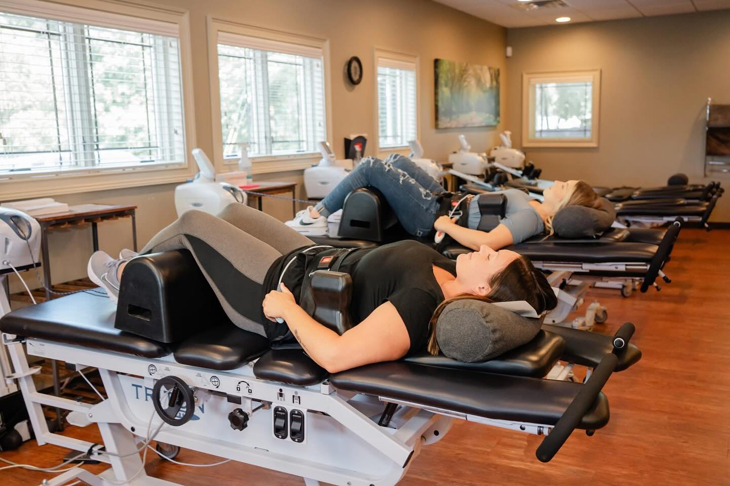 Two patients undergoing non-surgical spinal decompression therapy on traction tables in the practice's treatment room