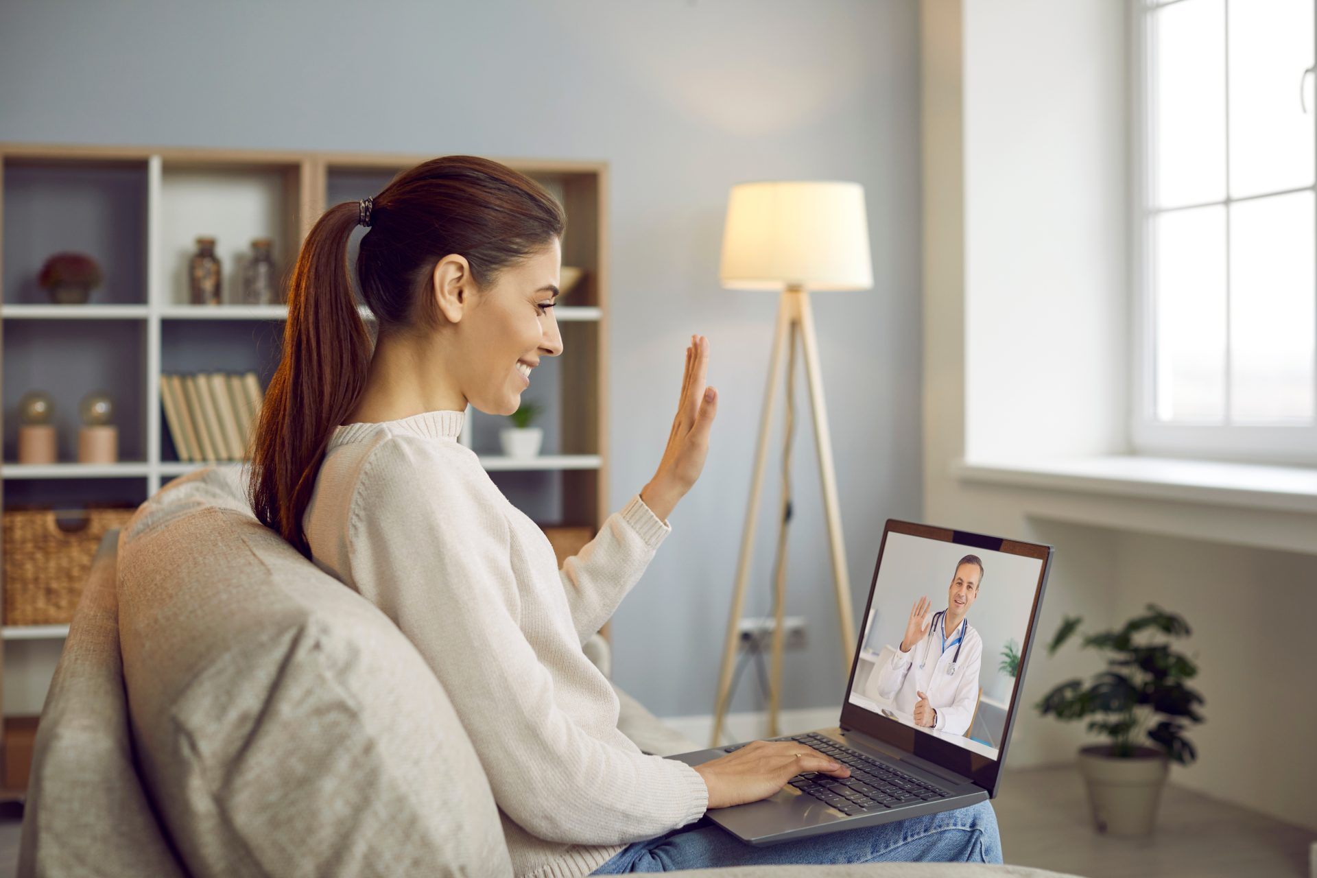 Image: An adult sitting at a kitchen table with a laptop, speaking with a provider on a video call. This shows the at-home setting of a first virtual psychiatry visit.