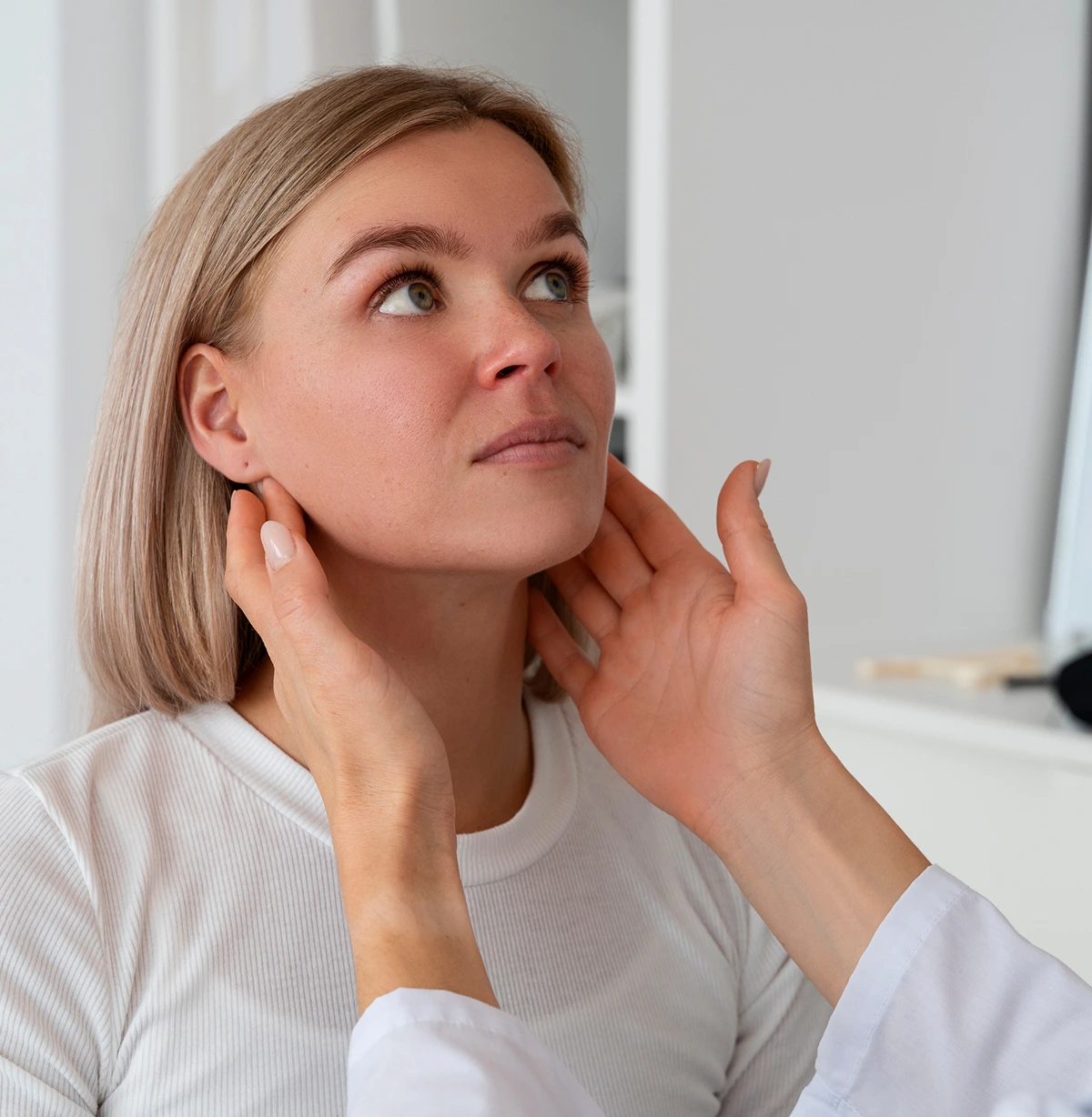 Clinician's hands feeling the side of a woman's neck, the lymph node check that is part of an oral cancer screening