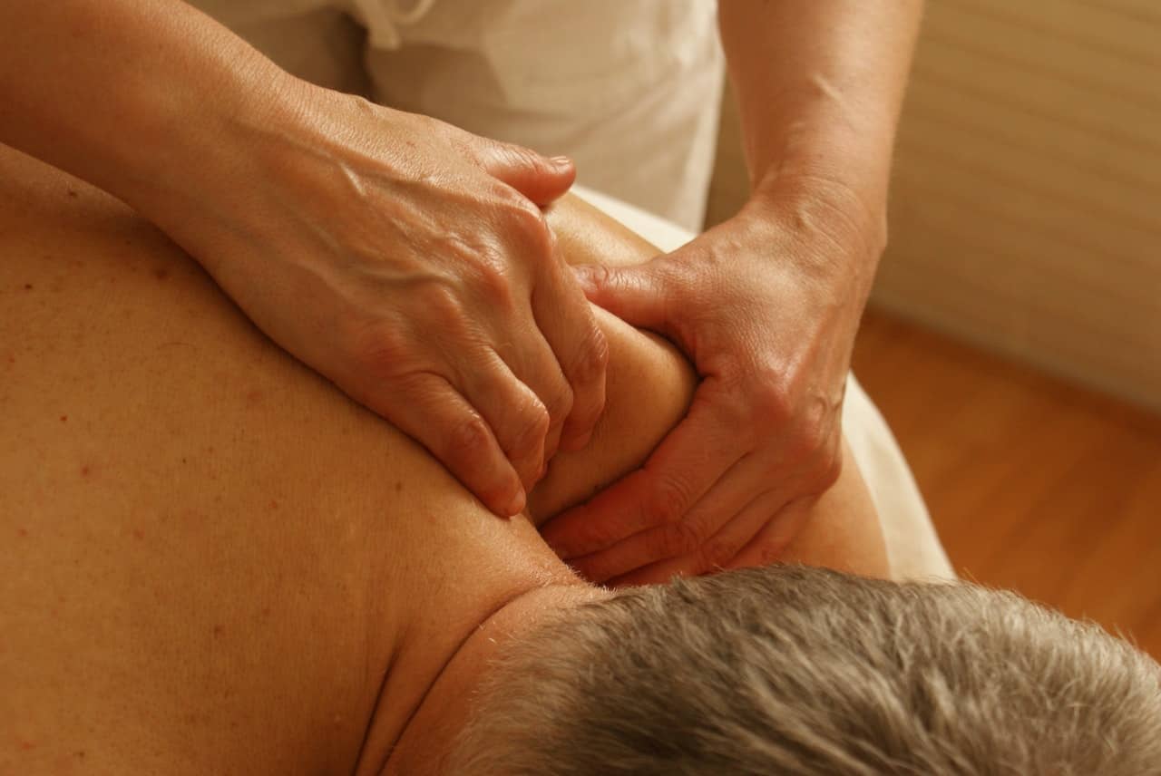 Close-up of hands working deep tissue massage into a patient's shoulder and neck