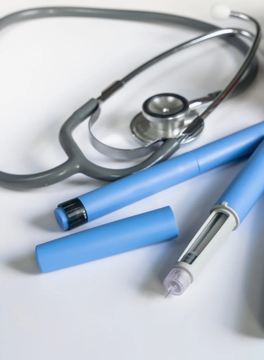 Blue GLP-1 style injection pens and a stethoscope on a white surface