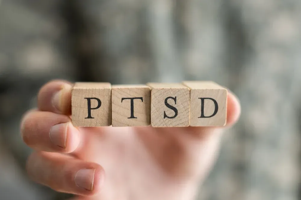 A hand holding wooden letter blocks that spell PTSD
