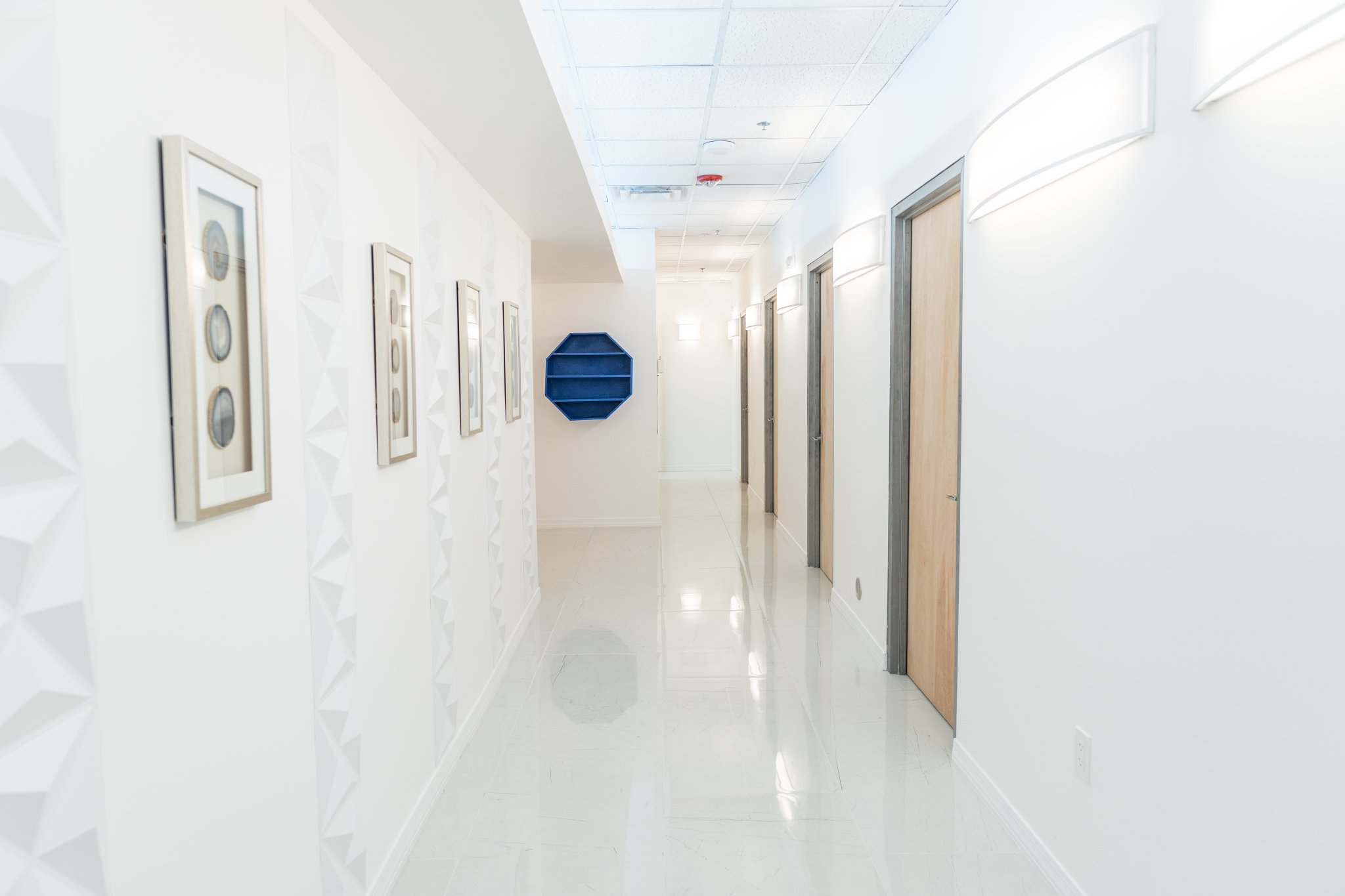 Bright clinic hallway with wood treatment-room doors at BL Medspa