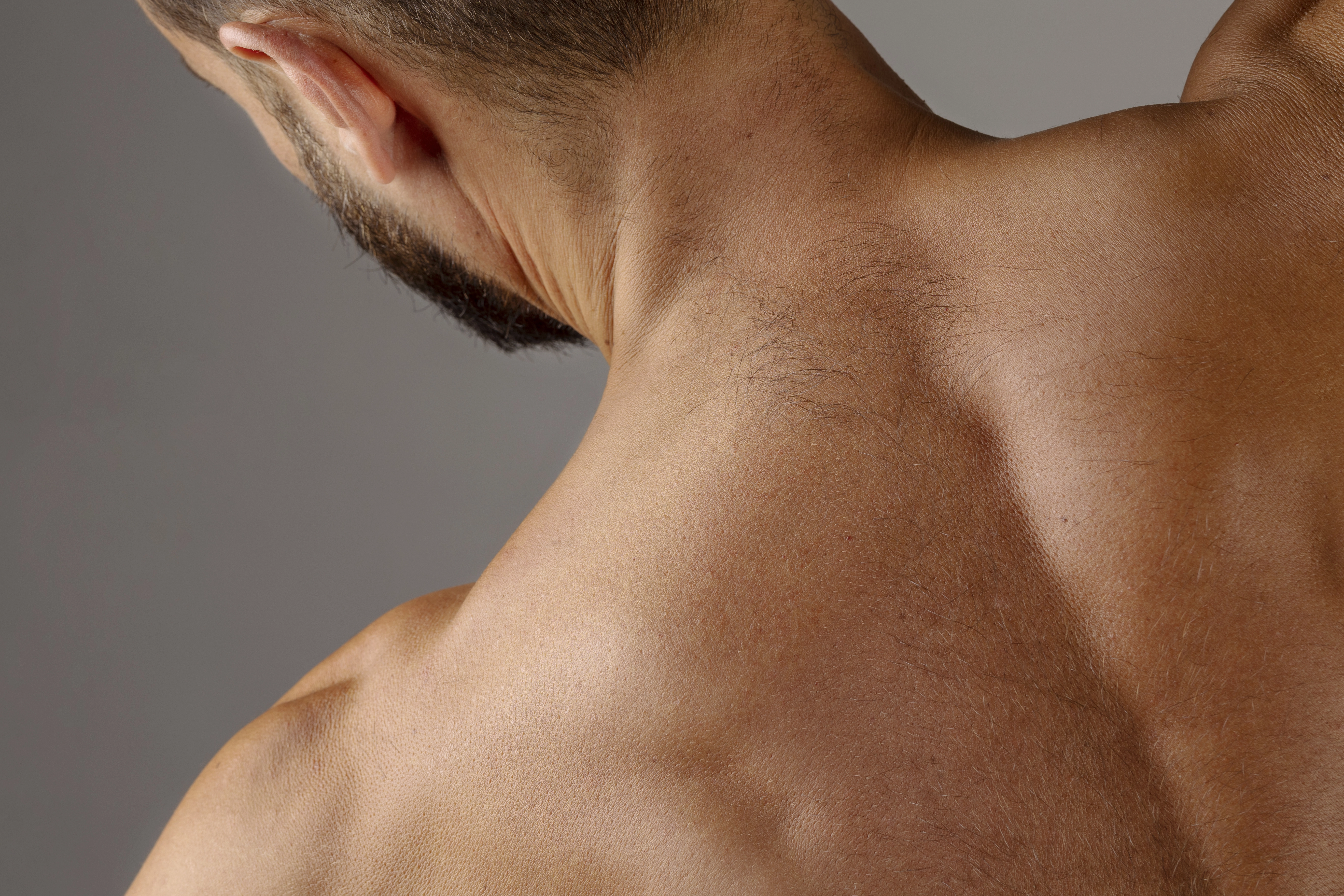 Close-up of a man's neck and upper back showcasing smooth skin, likely for a laser hair removal treatment