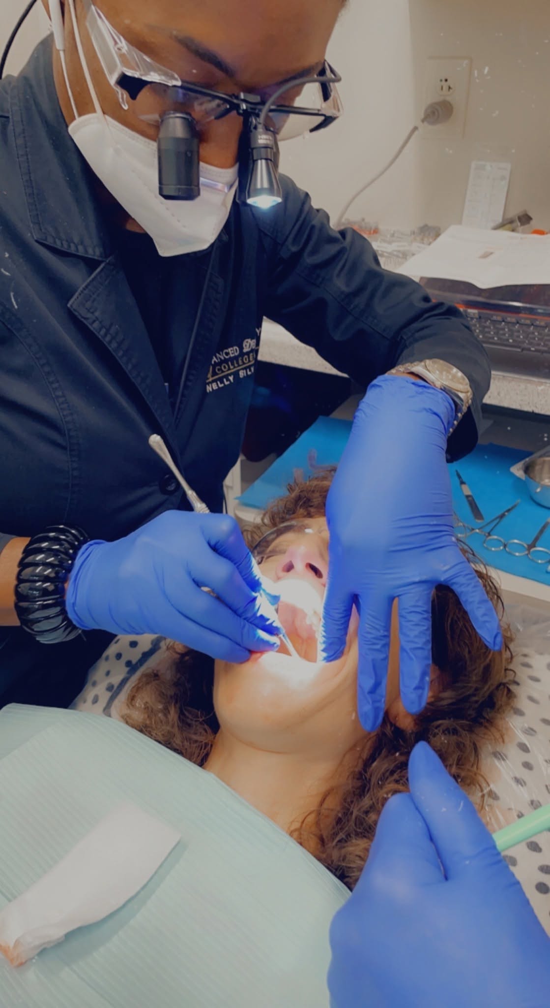 Dr. Nelly Silva wearing loupes examines a patient's teeth in the dental chair at our Collegeville office