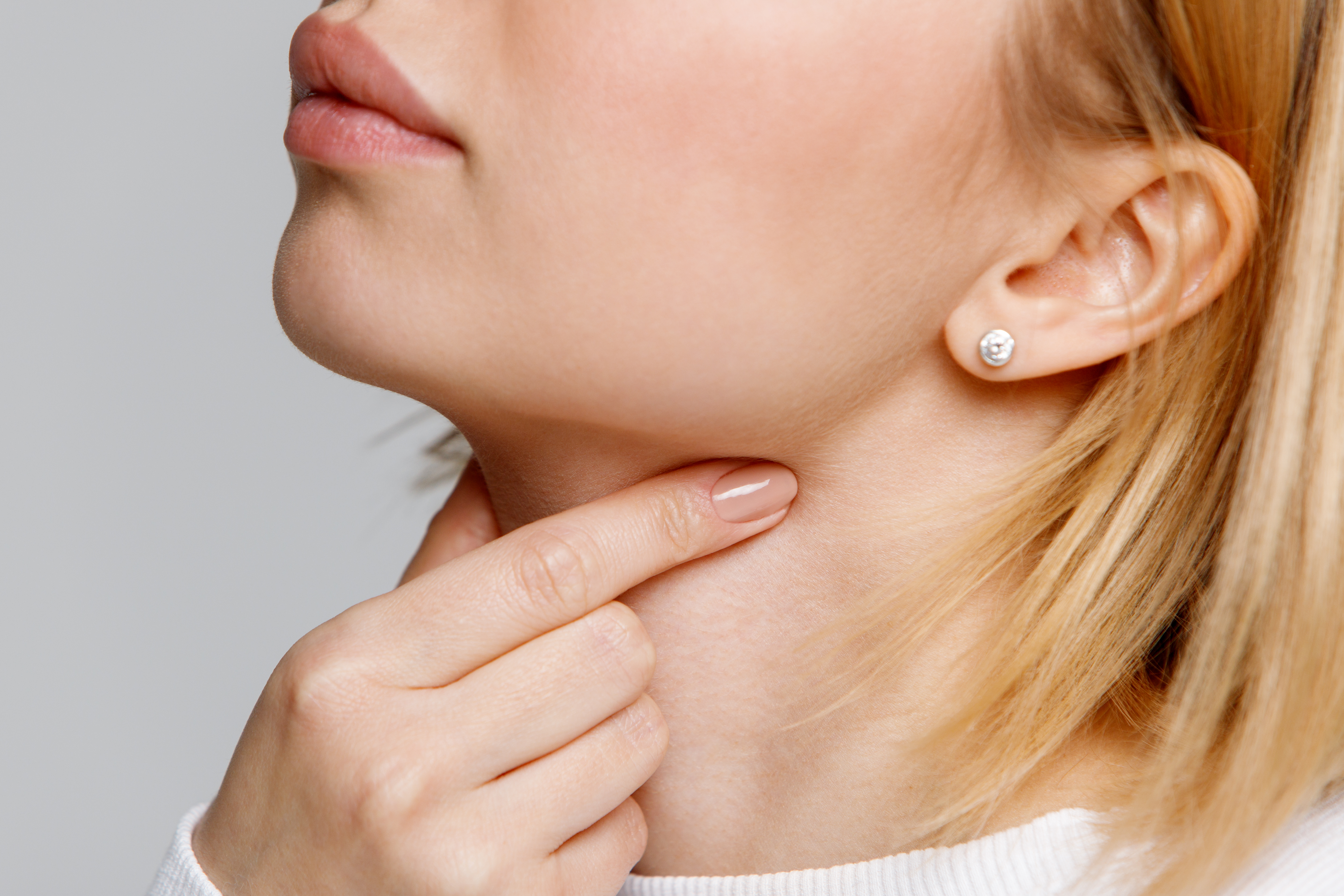 Close-up of a woman touching her neck to check her thyroid gland, illustrating thyroid disorder concerns.