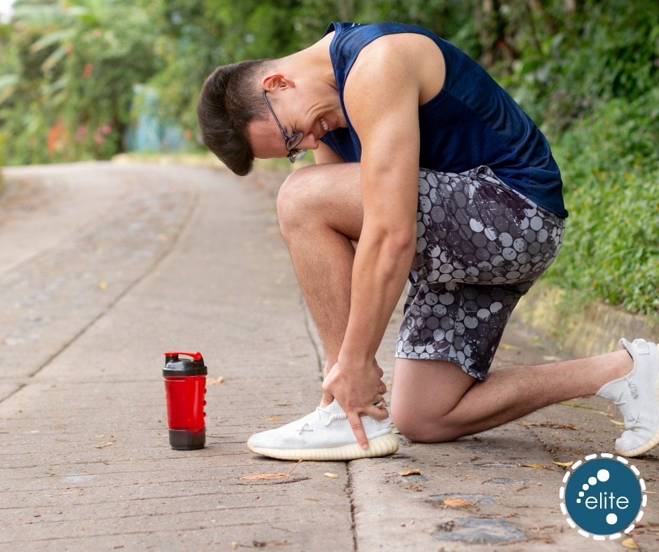 A man kneels on a path clutching his ankle in pain while out running, illustrating an ankle sprain injury for a podiatry prac