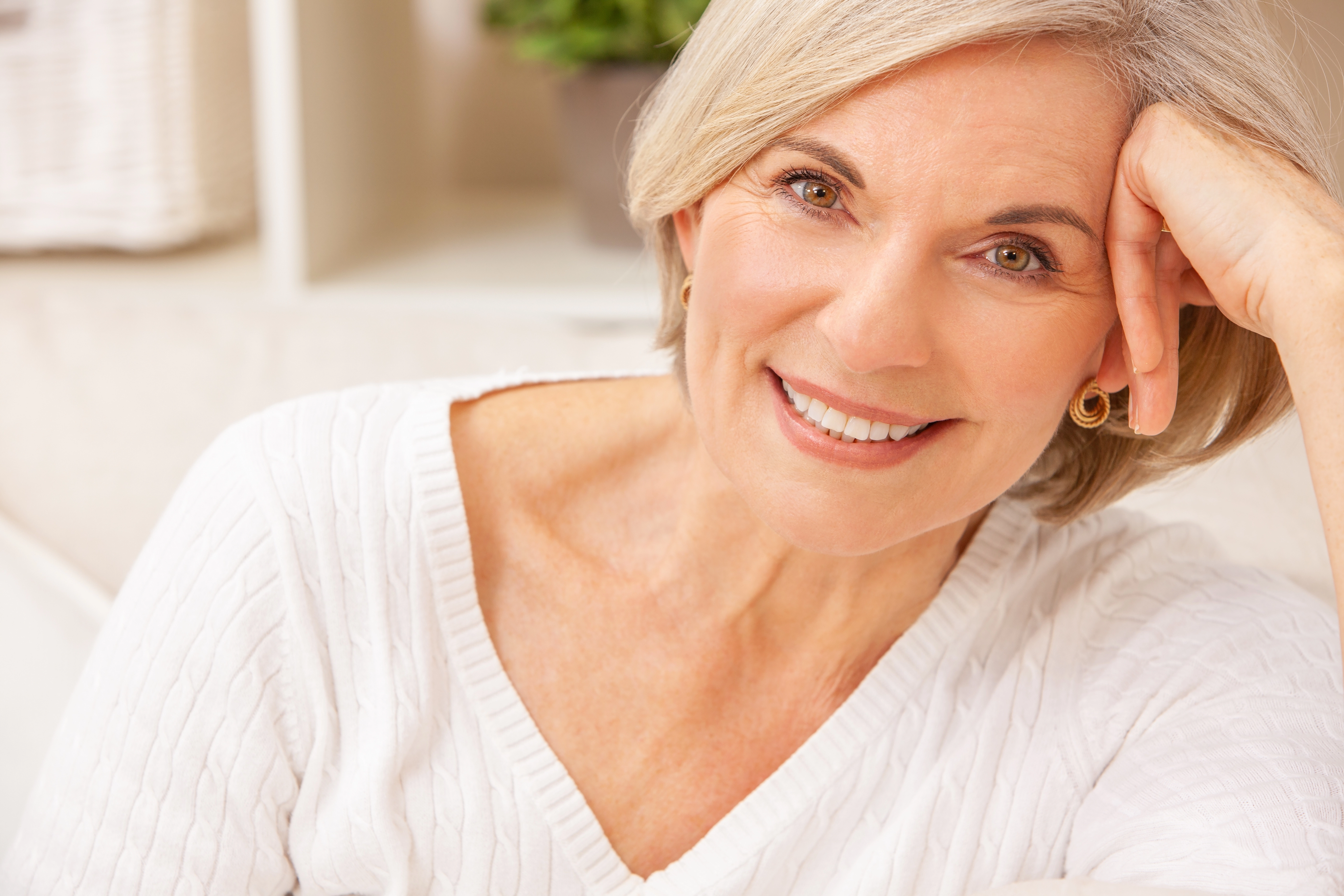 Smiling mature woman with short blonde hair resting her chin on her hand