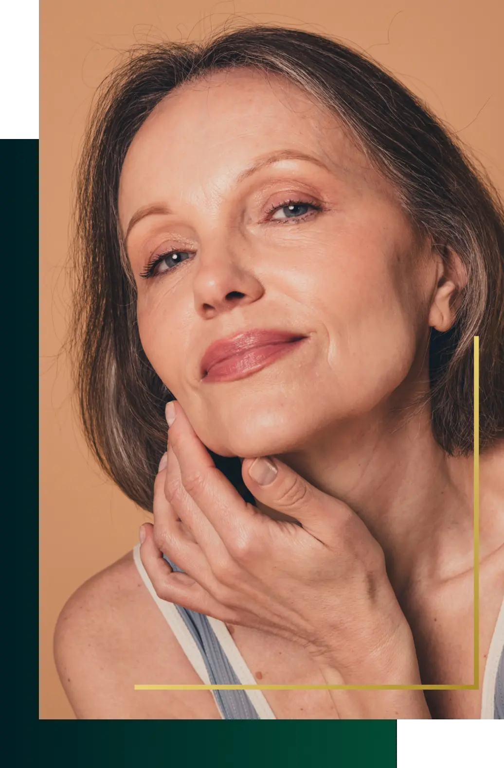 Mature woman with smooth skin around her eyes resting her chin on her hand against a warm tan backdrop