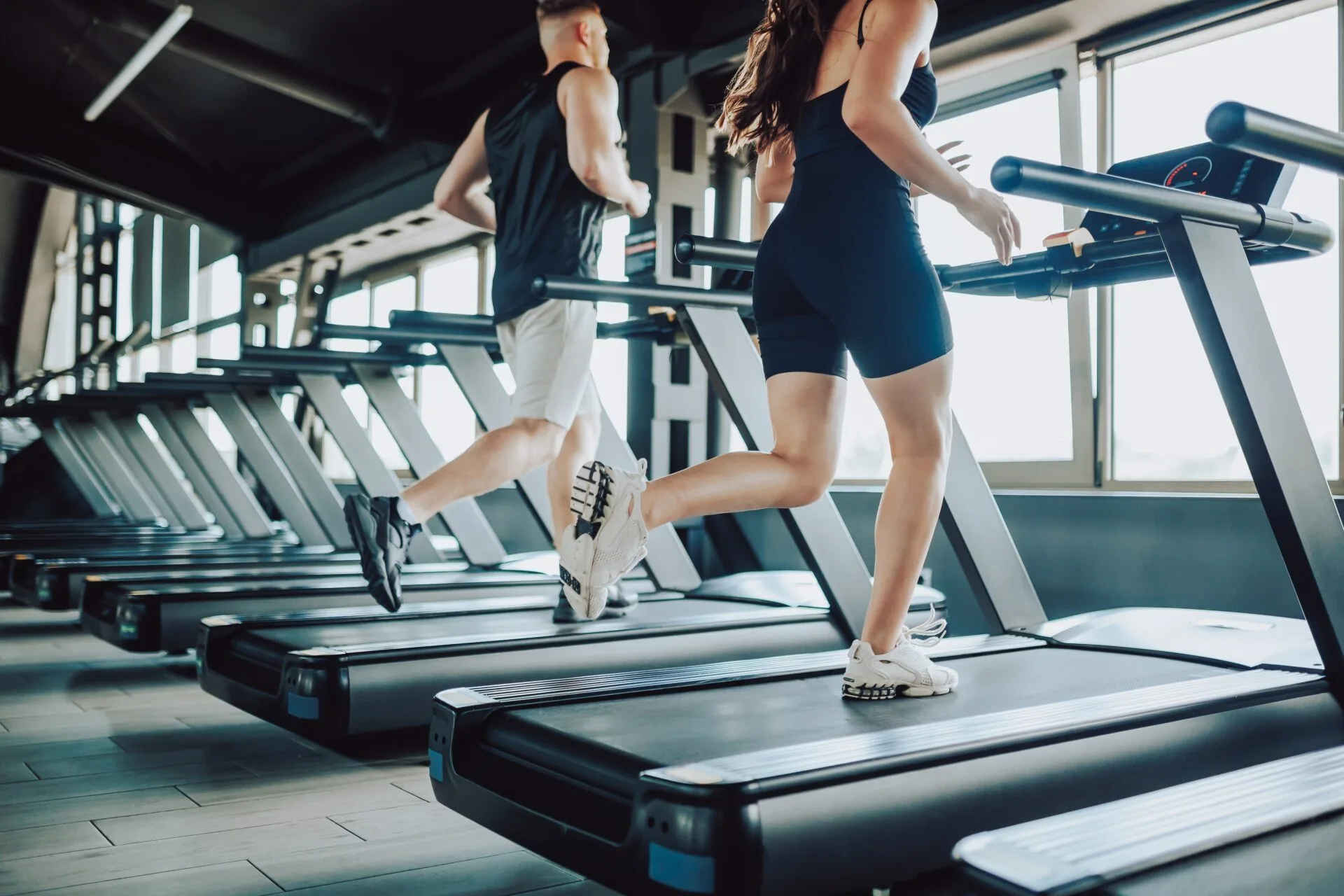 A man and woman running on treadmills in a modern gym, illustrating exercise activity referenced in a blog about post-rhinopl